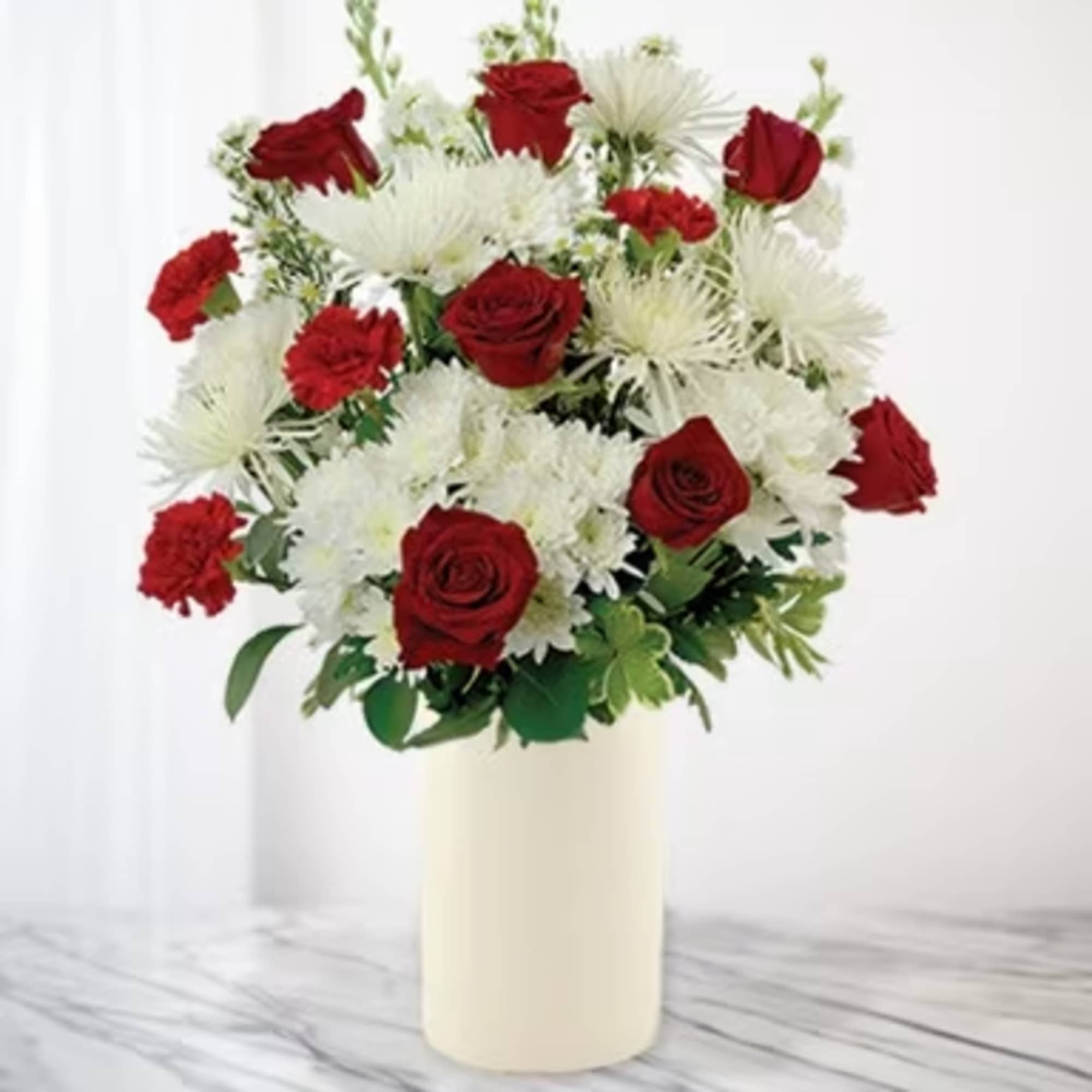 Red roses and white chrysanthemums in a cream vase