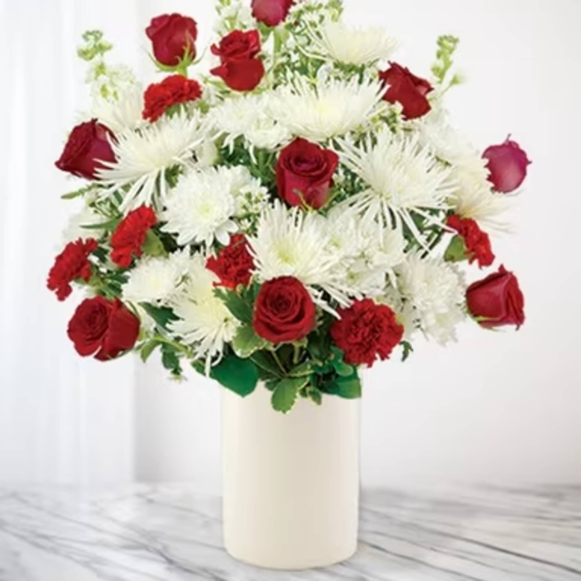 Red roses and white chrysanthemums in a tall cream vase