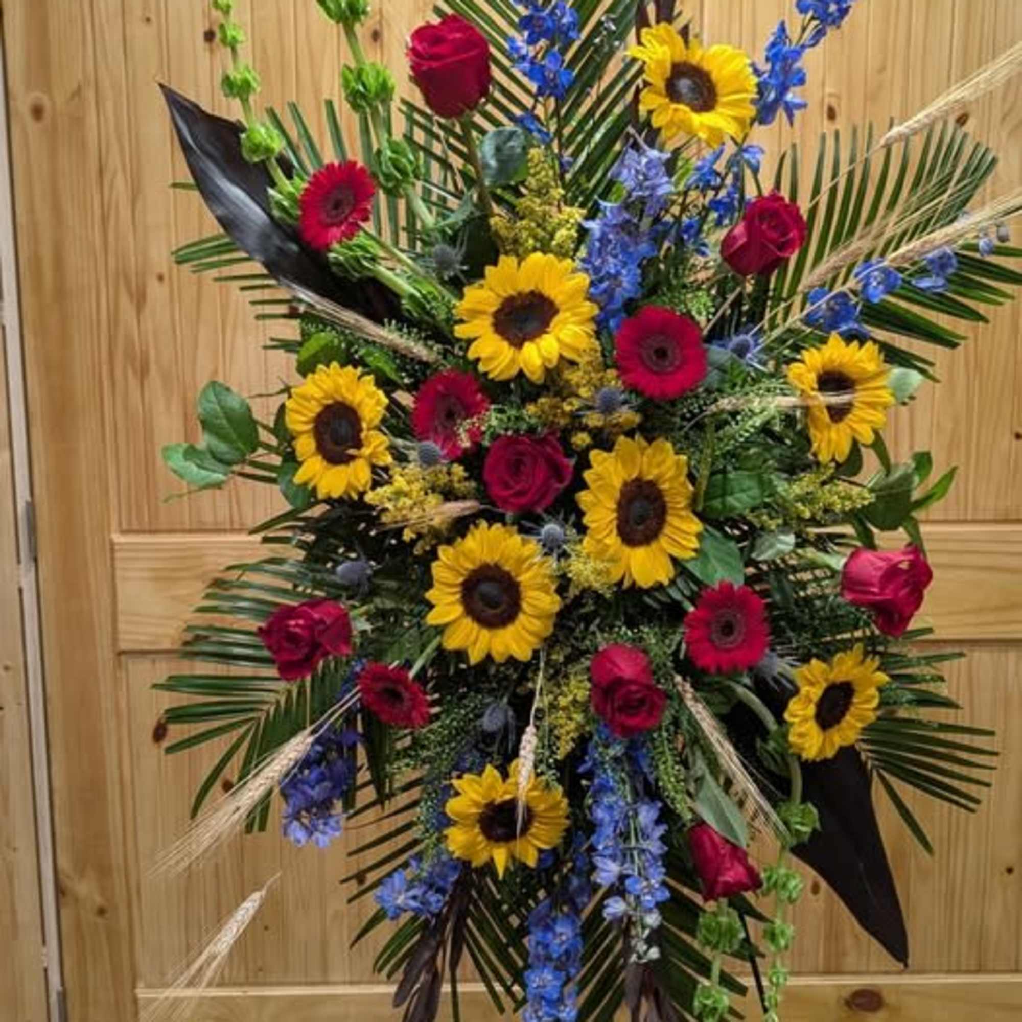 Standing Spray Includes, Red Roses, Blue Delphinium, Sunflowers and Bells of Ireland