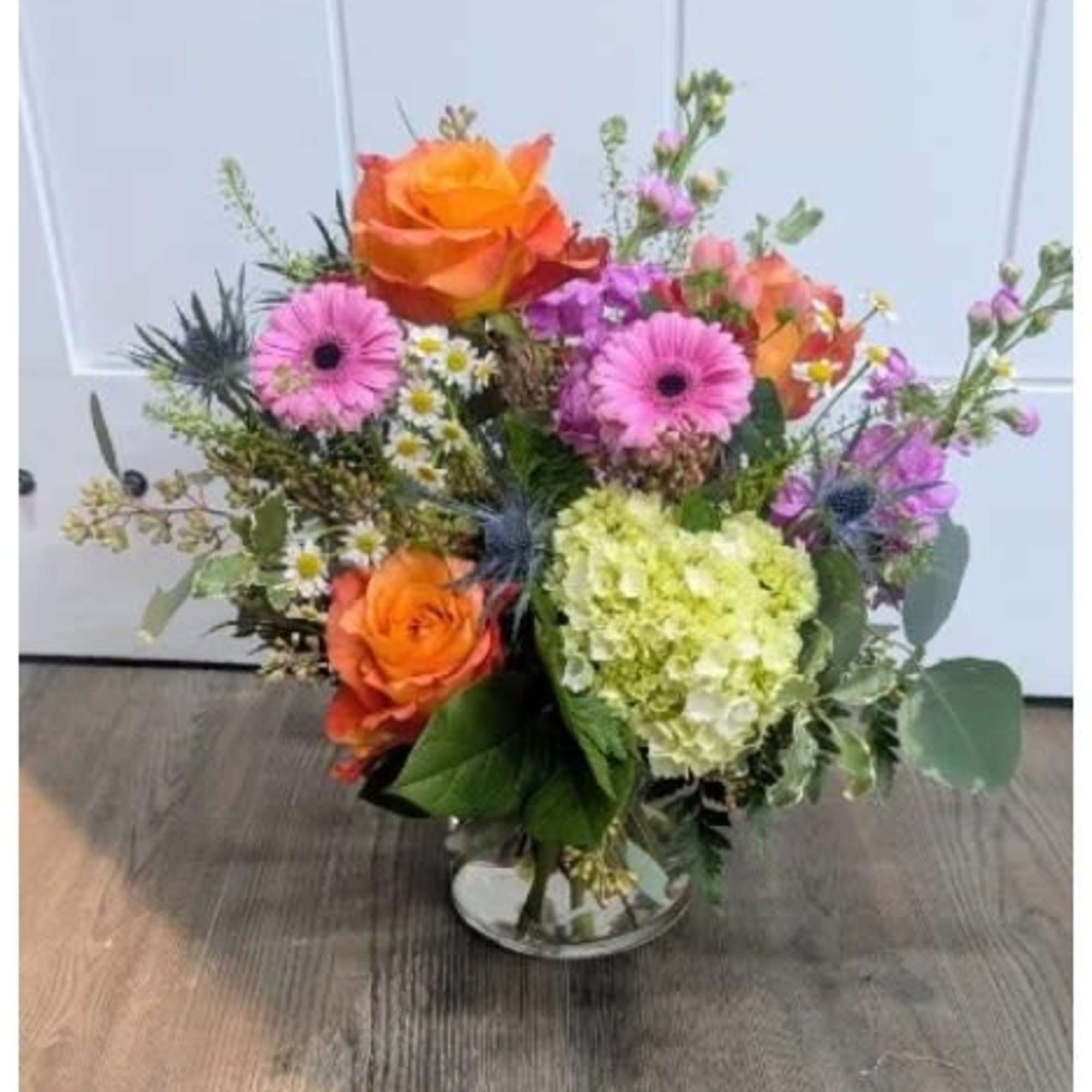 Bright orange roses and pink gerbera daisies take center stage in this