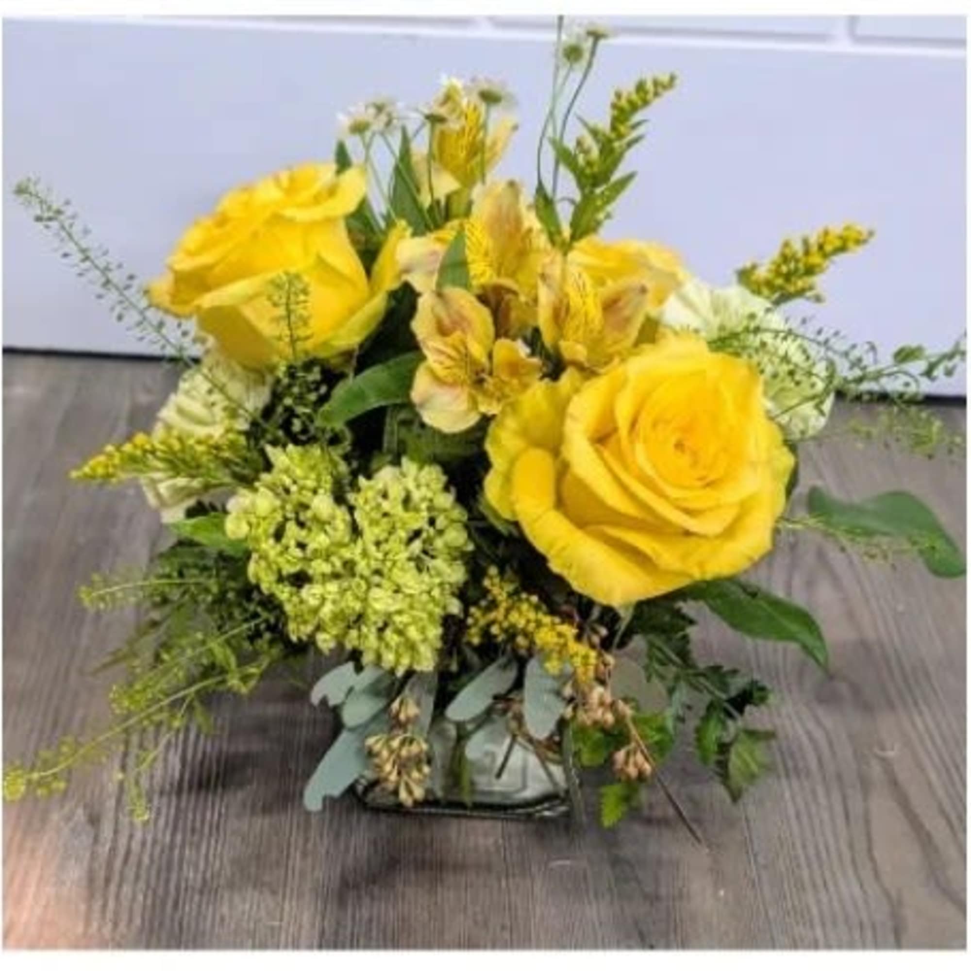 Large yellow roses take center stage in this sunny everyday arrangement, paired