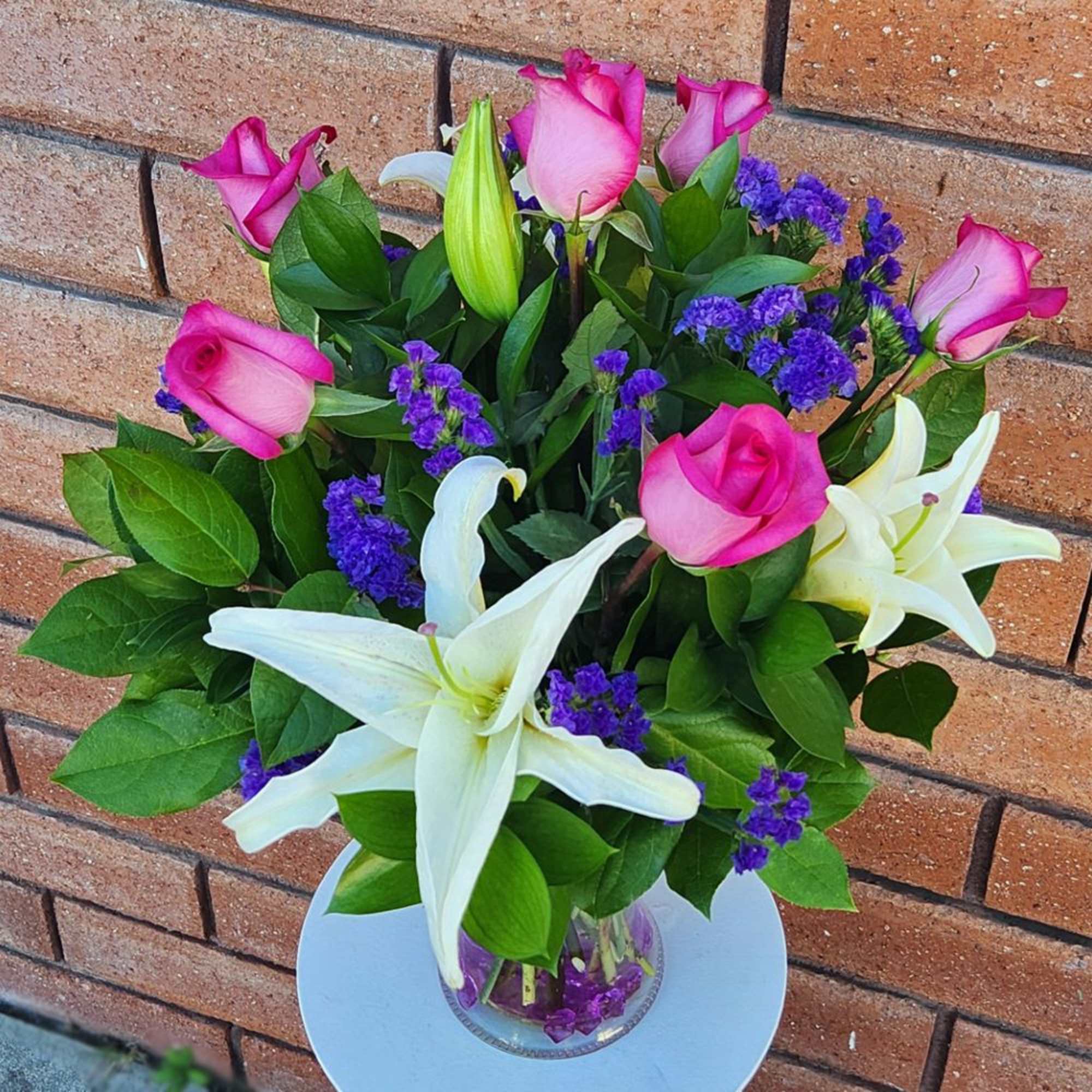Pink roses and white lilies in a clear glass vase