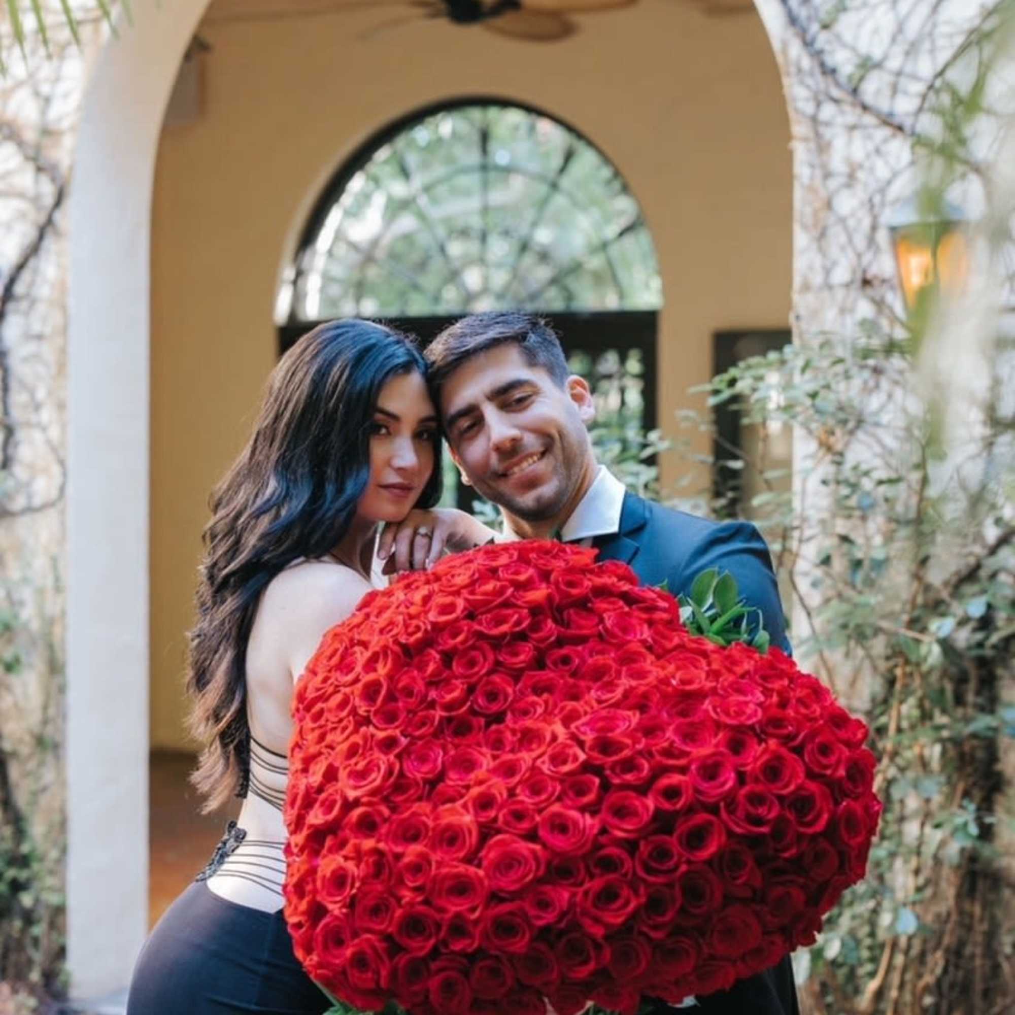 Couple holding a large bouquet of red roses