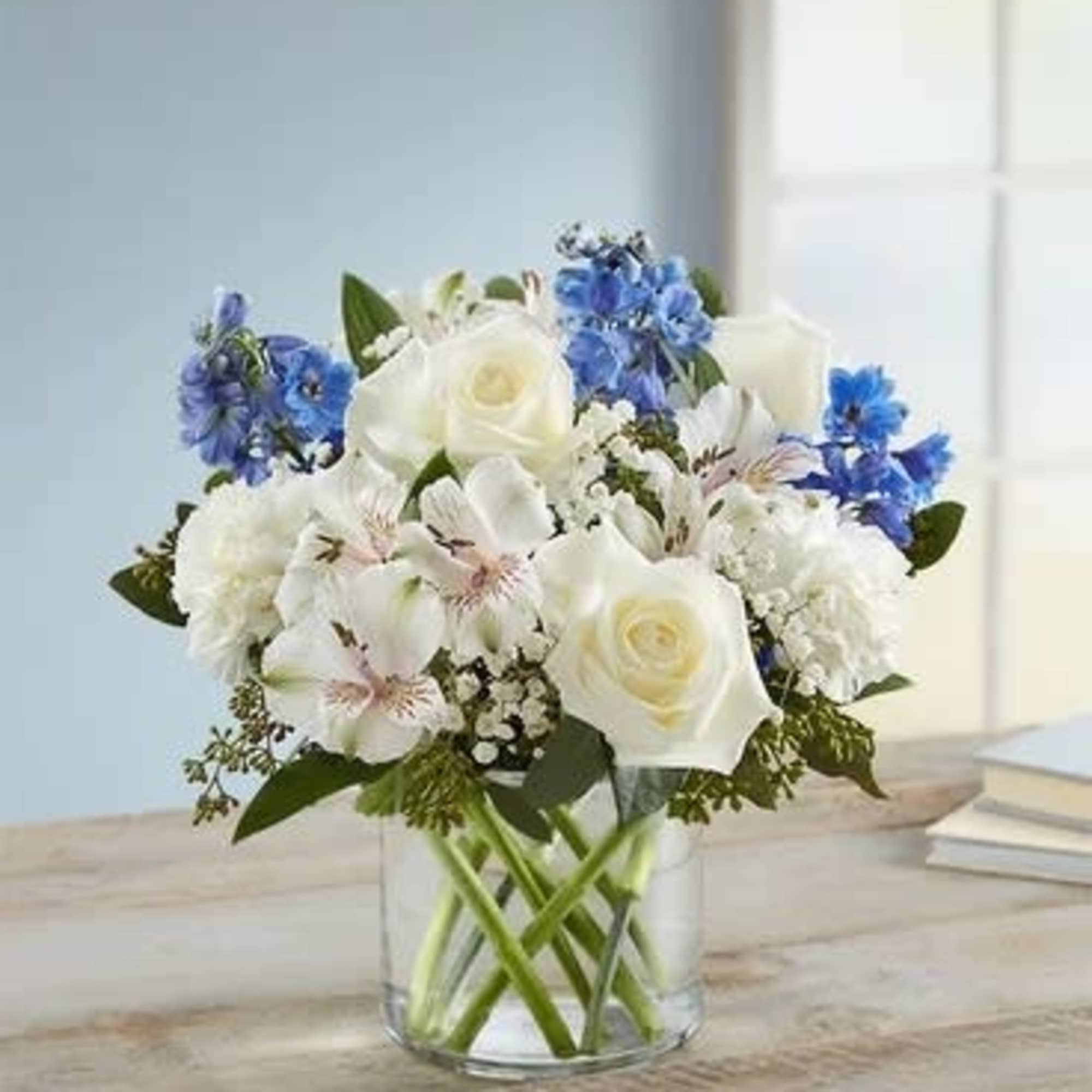 White and blue mixed bouquet in a clear glass vase
