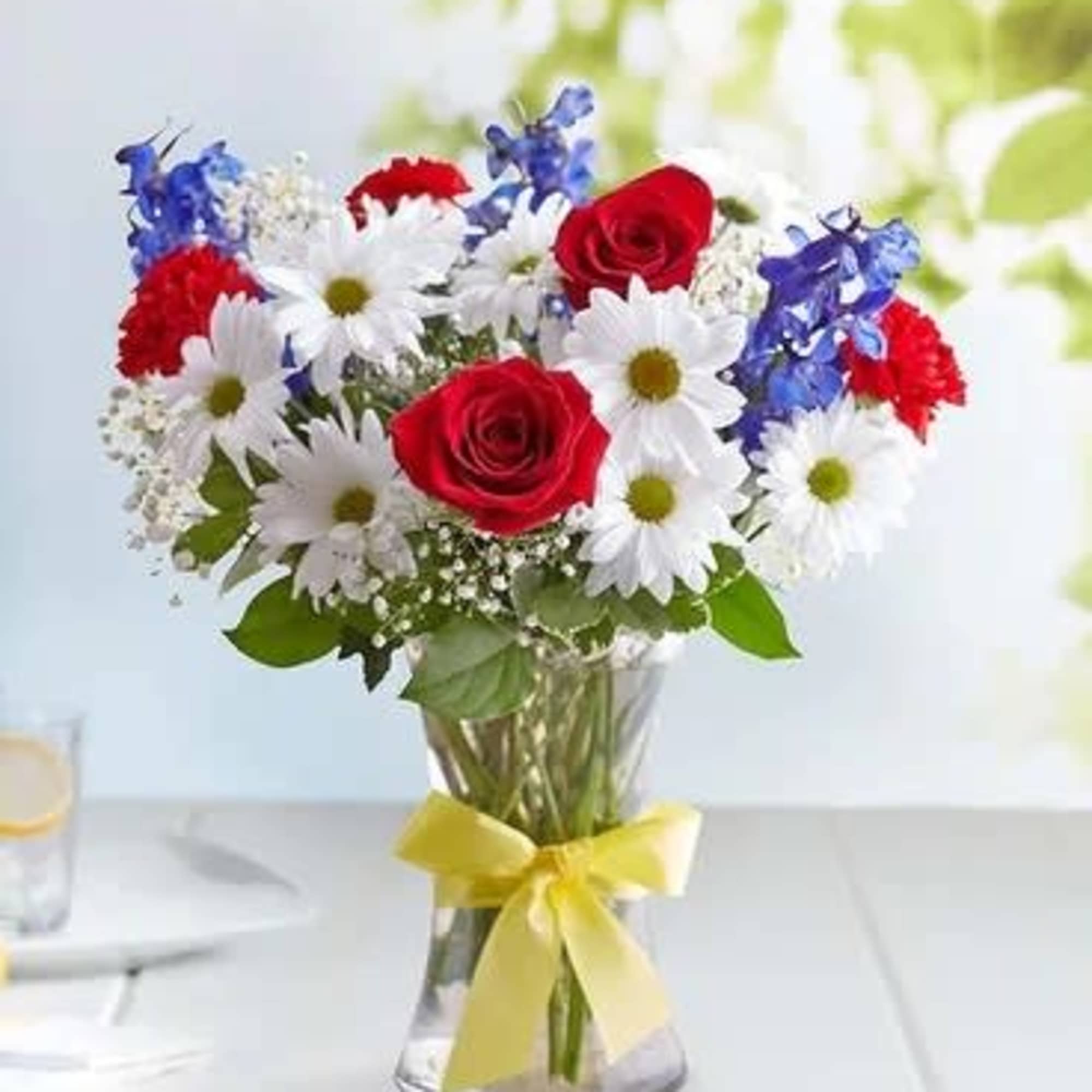 Bouquet of red roses and white daisies in a clear glass vase