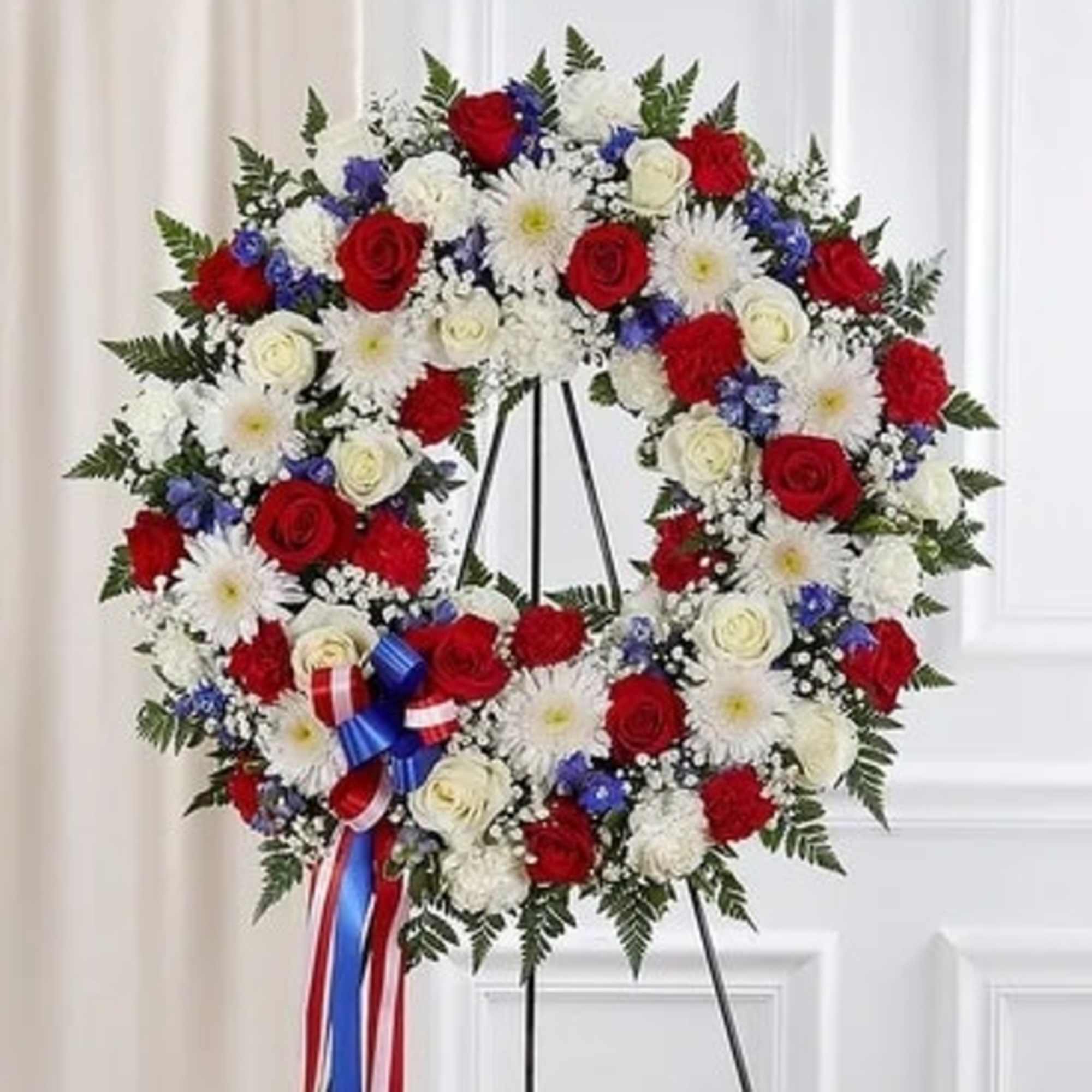 Red, white, and blue floral wreath on a stand with ribbon