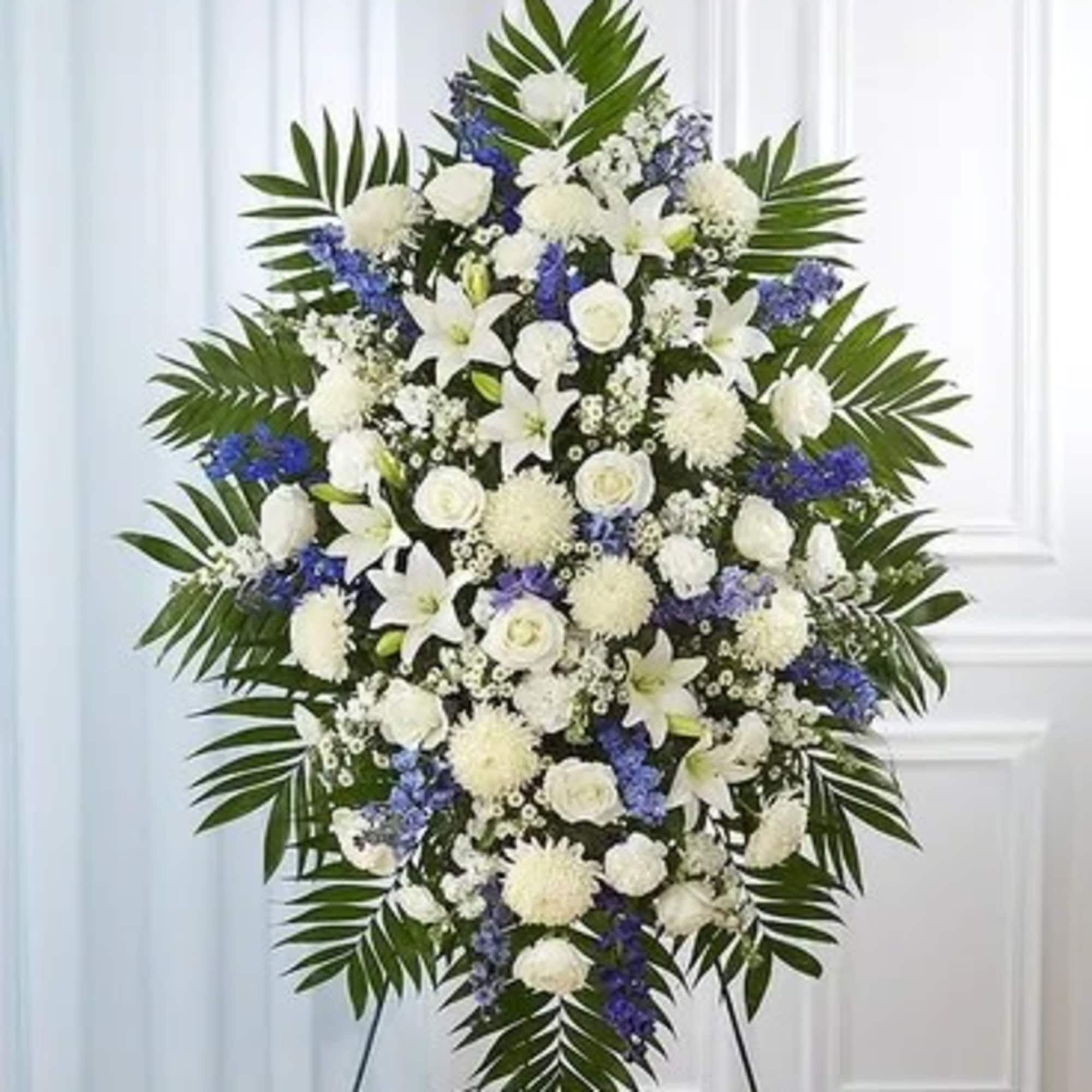 Large white and blue funeral spray on an easel