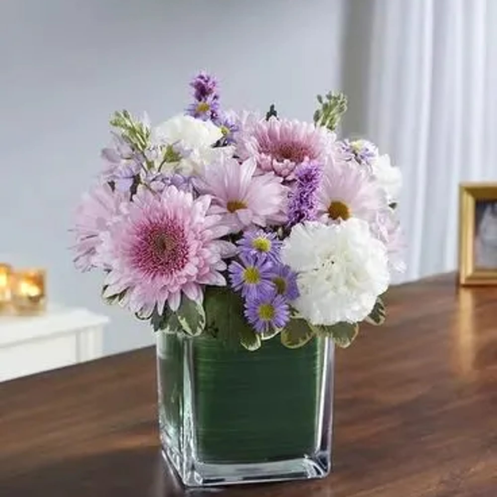 Pink and white daisy bouquet in a square glass vase