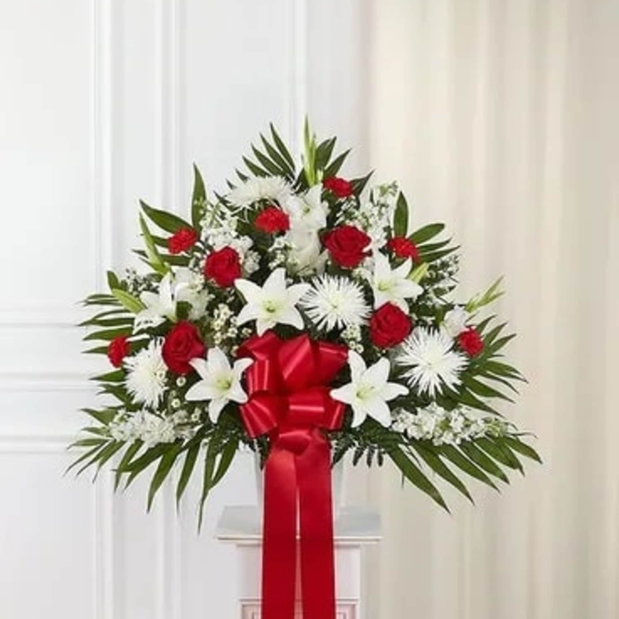 Standing floral spray with red roses, white lilies, and a red ribbon