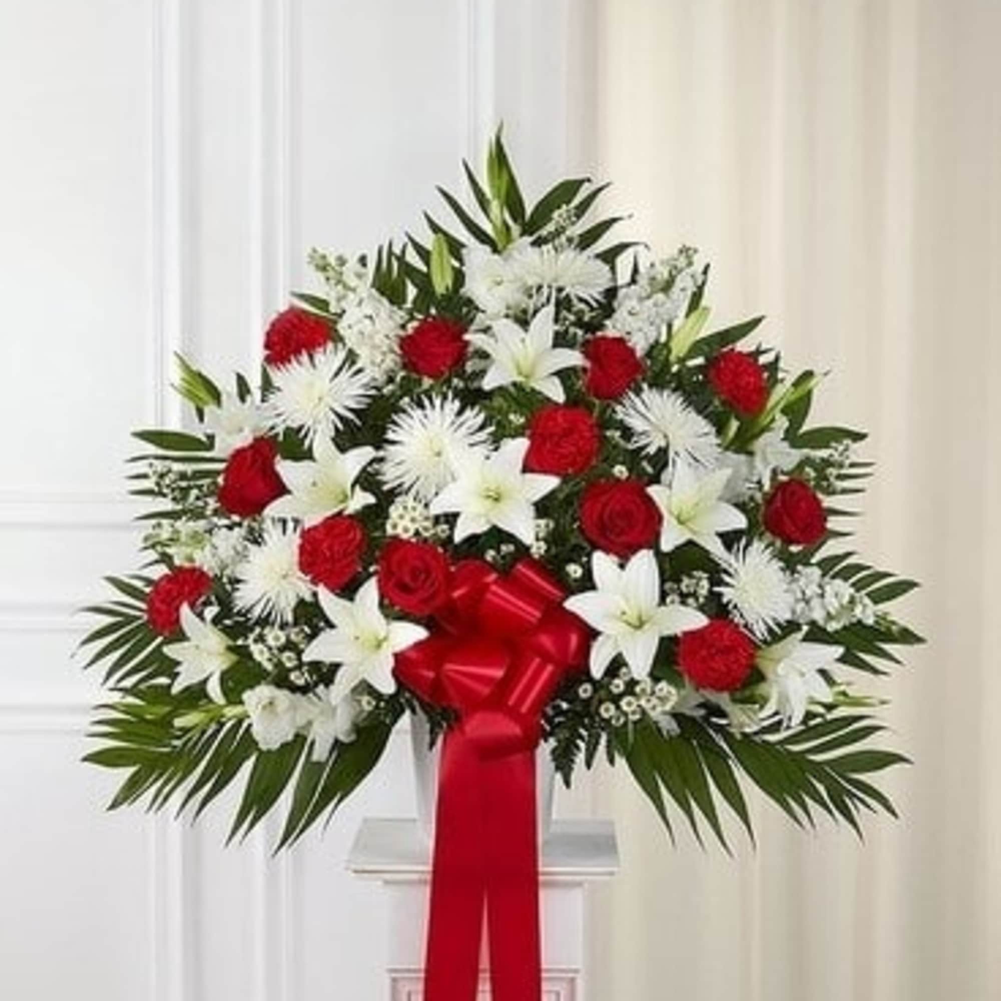 Standing floral spray with red roses and white lilies, tied with a red ribbon