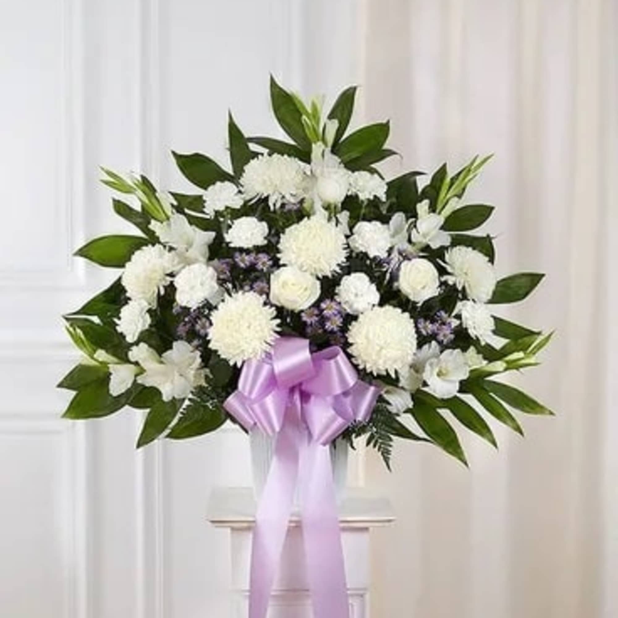 White funeral spray with a lavender ribbon on a stand