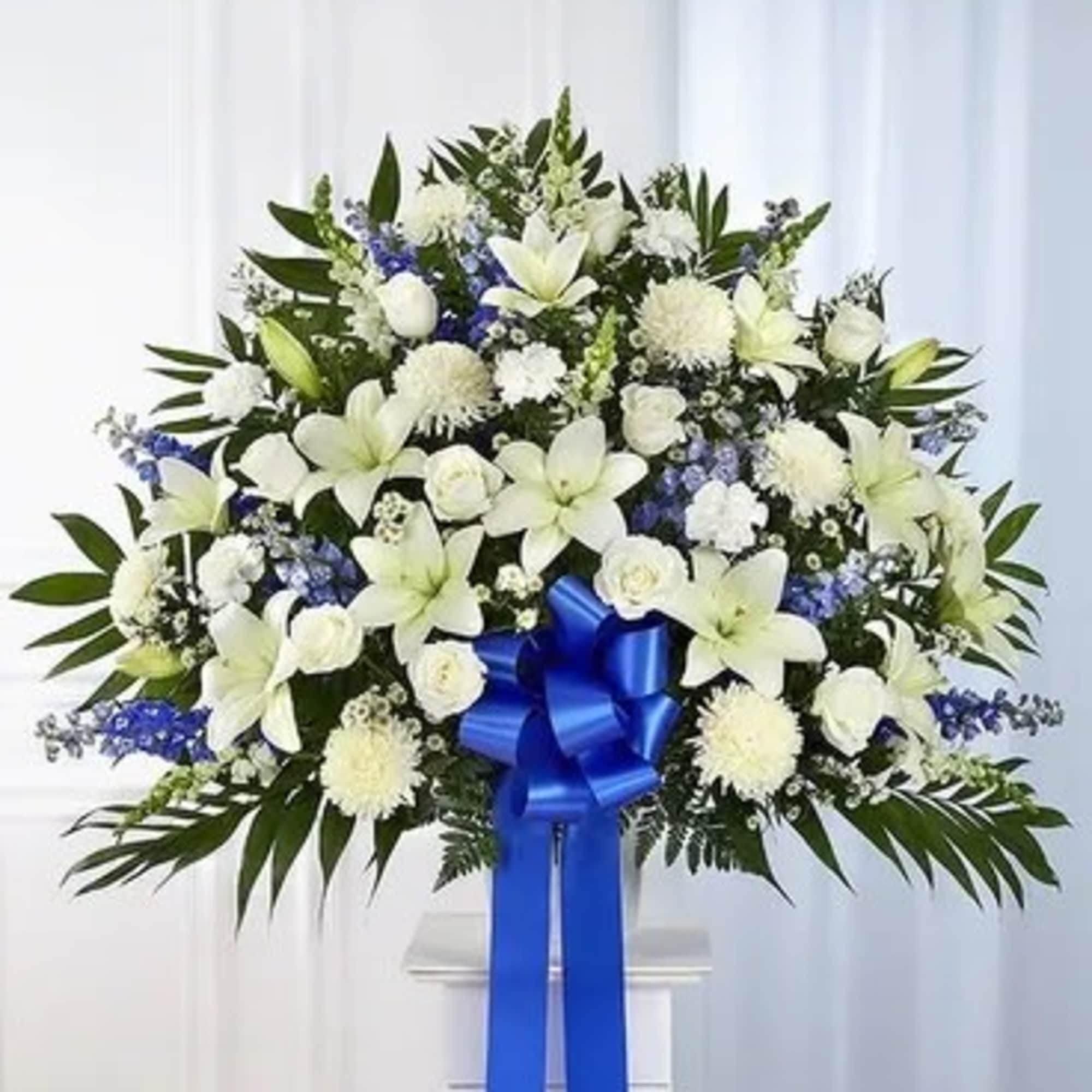 White floral standing spray with a blue ribbon