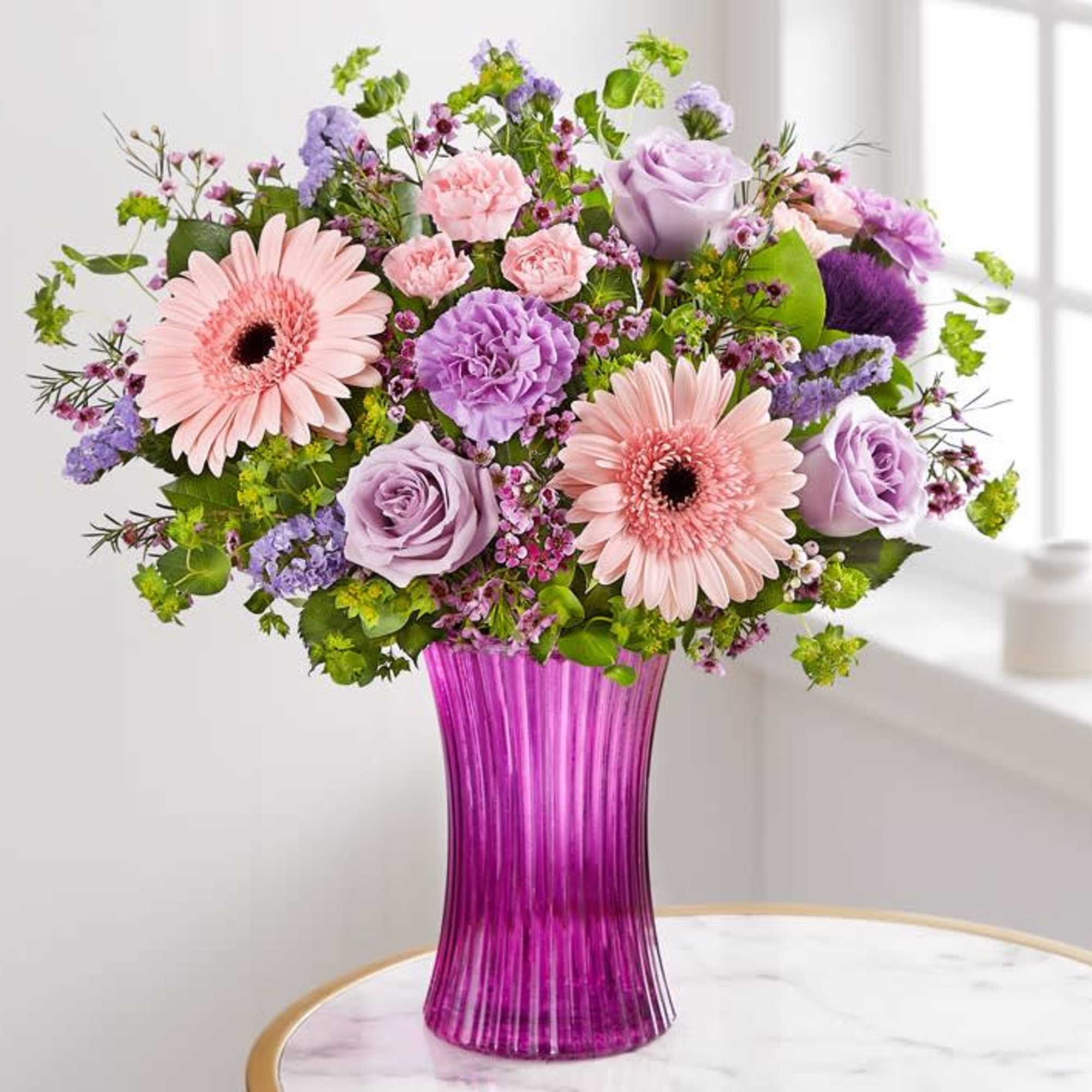 Pink and lavender mixed bouquet in a purple glass vase