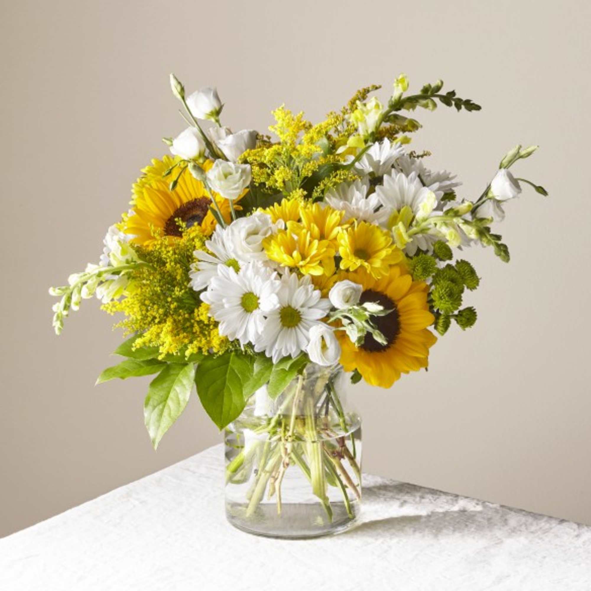 Bouquet of yellow sunflowers and white daisies in a clear glass vase