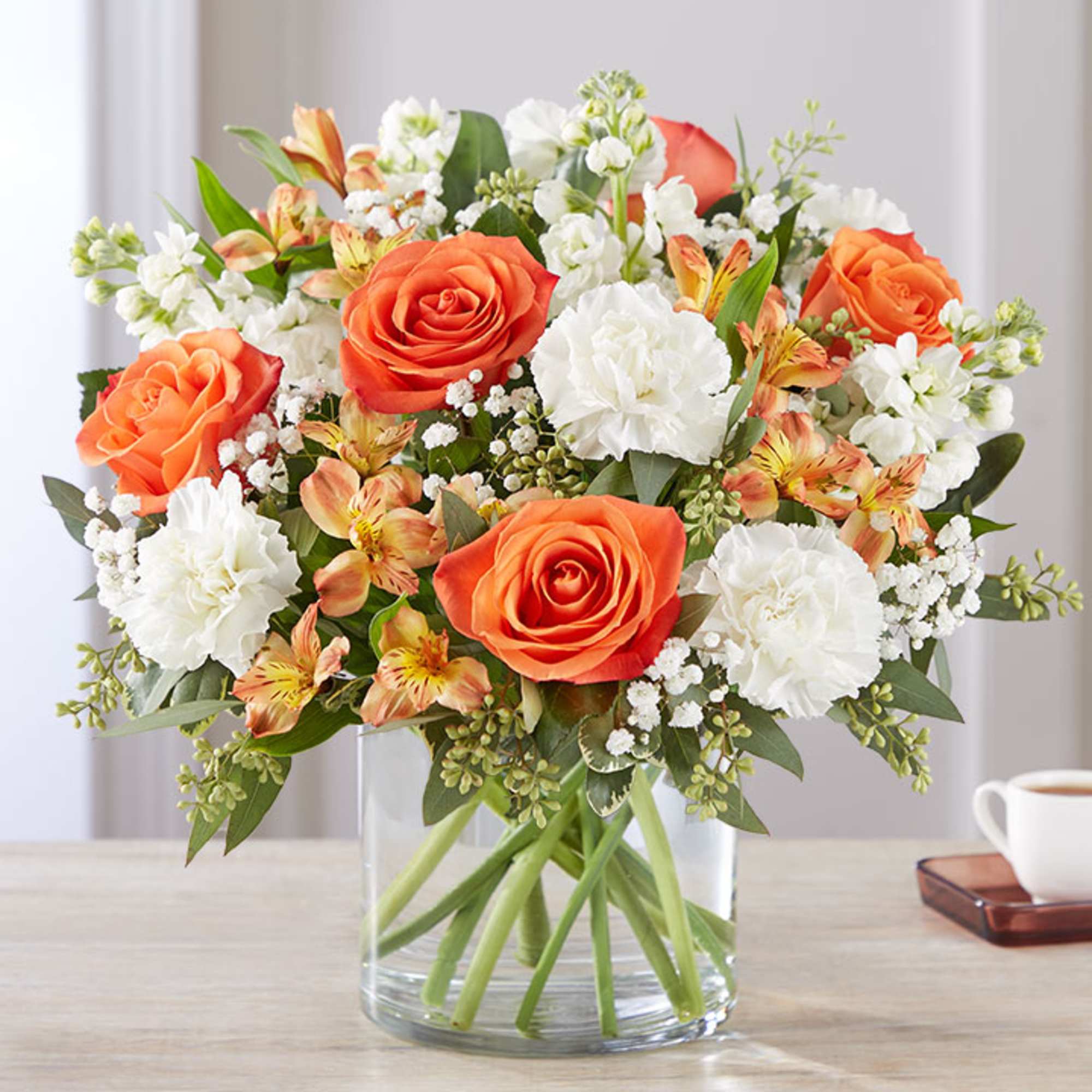 Orange roses and white carnations in a clear glass vase