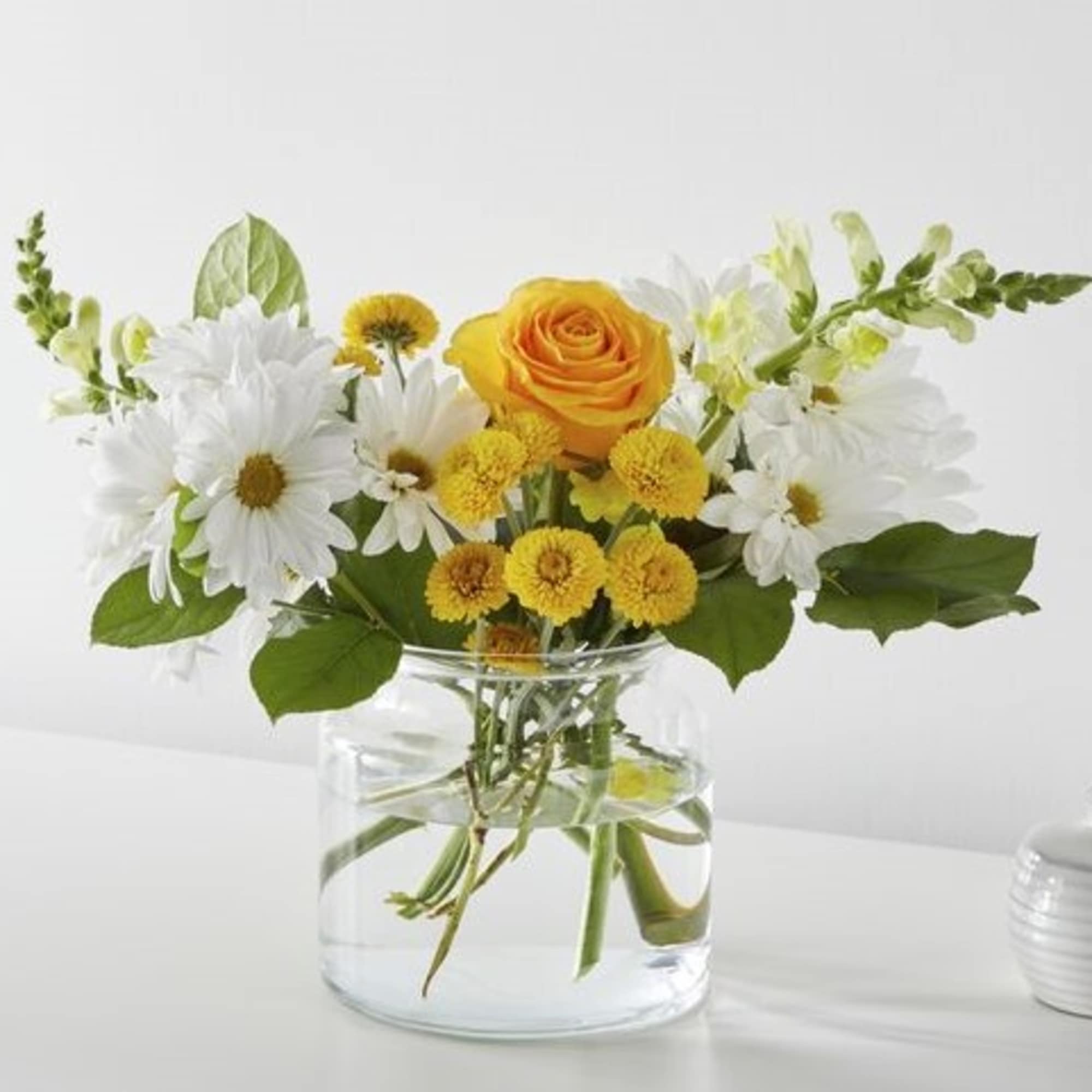 Yellow rose and white daisies in a clear glass vase