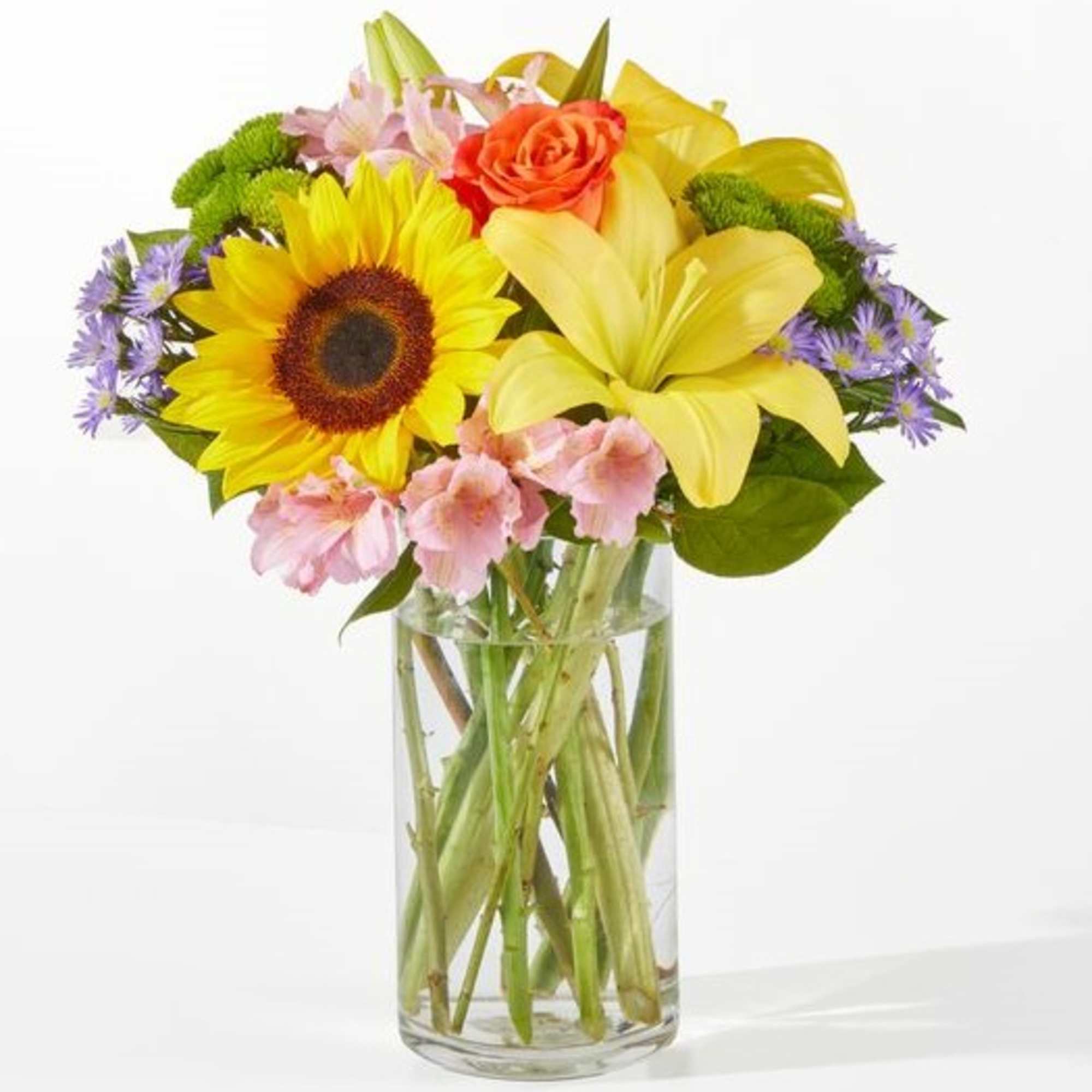 Bouquet of sunflowers, lilies, roses, and pink flowers in a glass vase