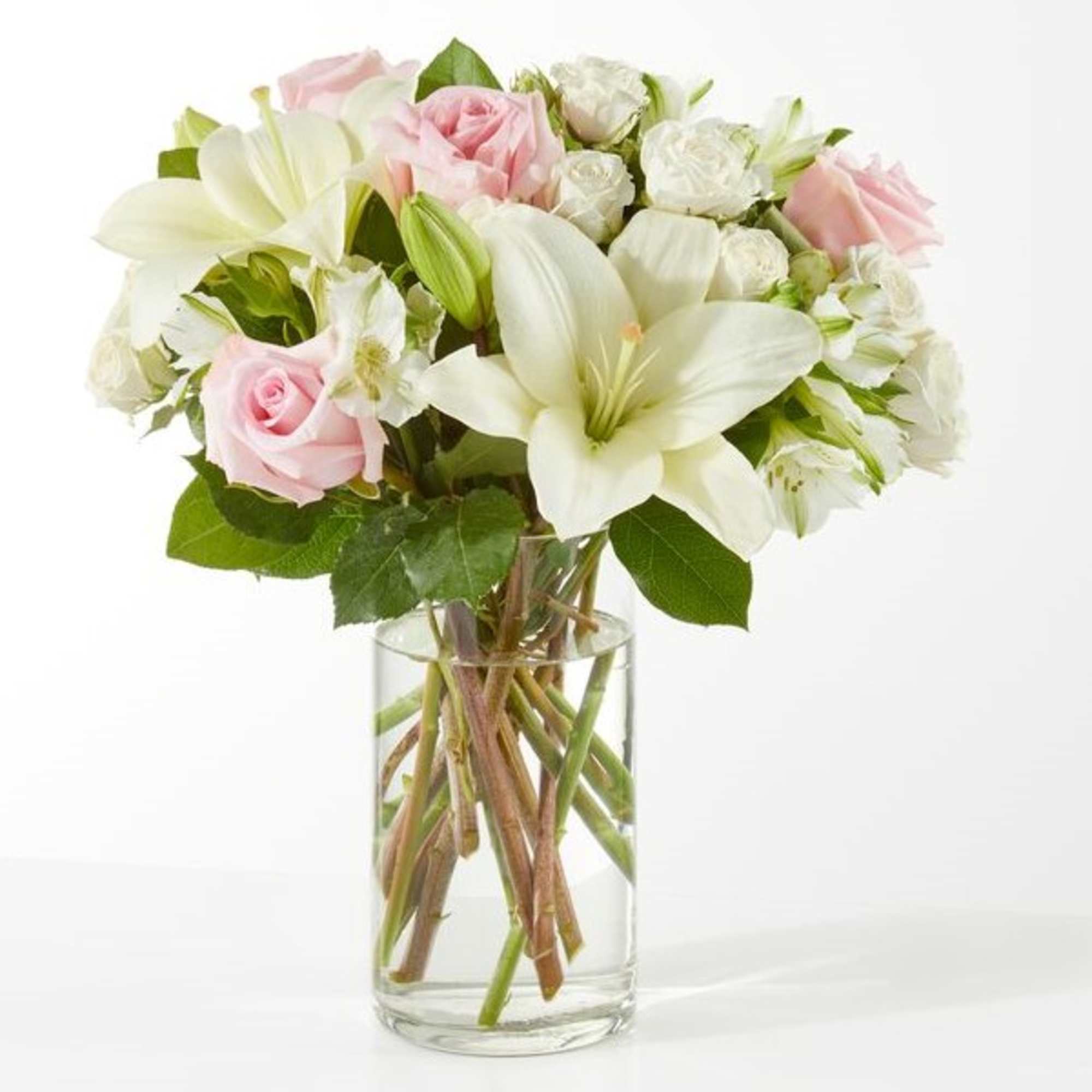 Pink roses and white lilies in a clear glass vase