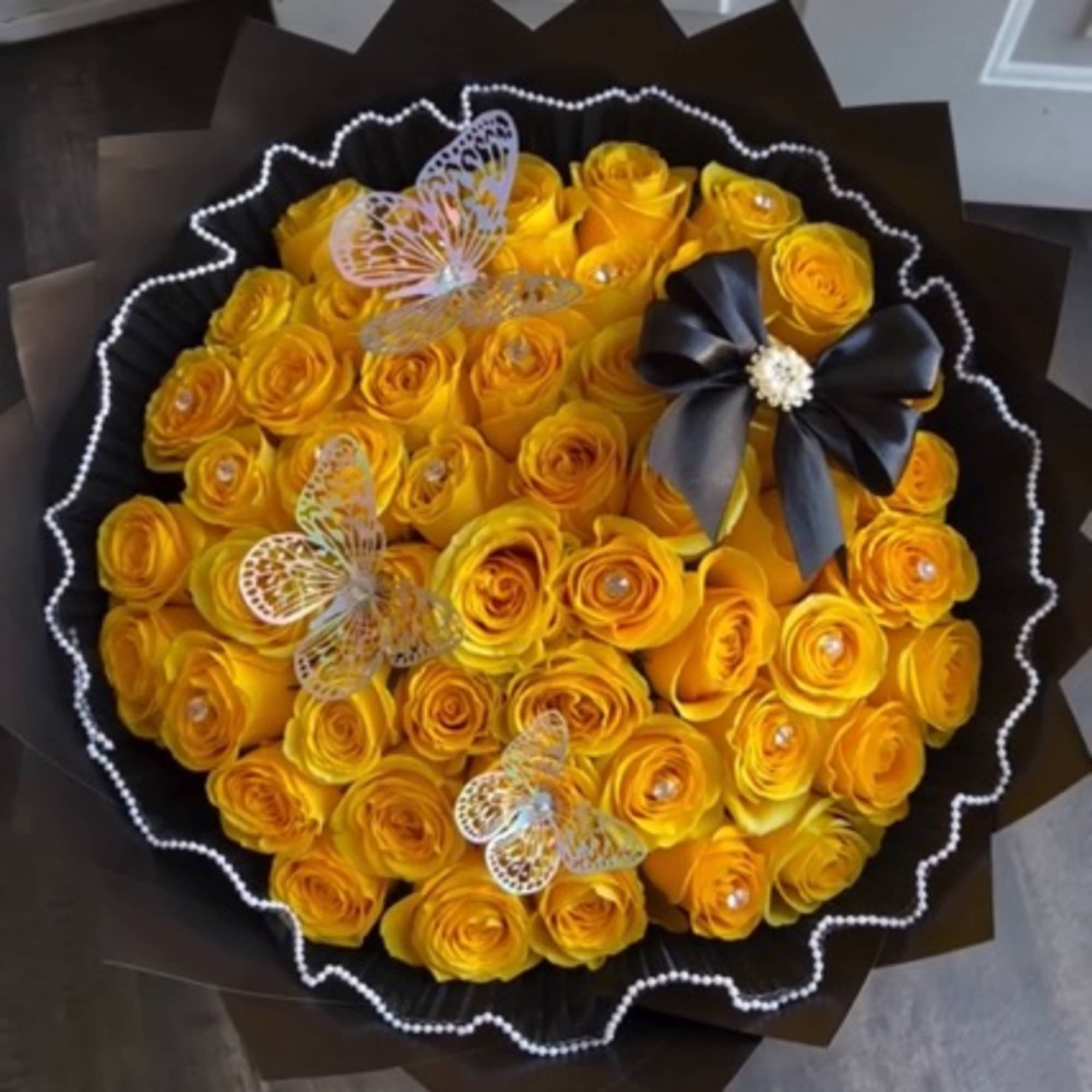 Bouquet of yellow roses with butterfly decorations and a black ribbon