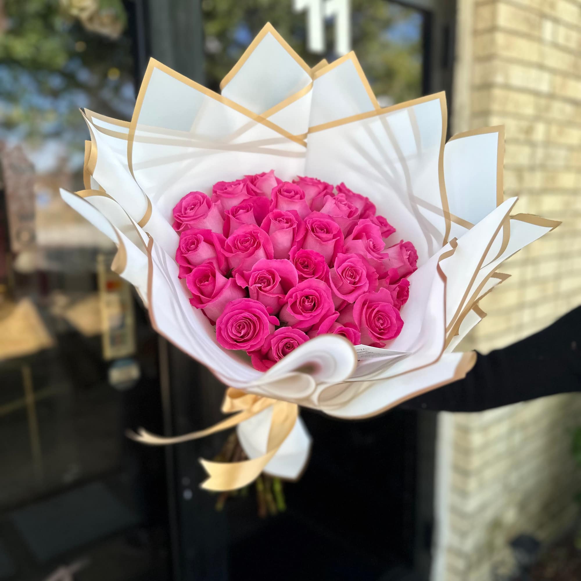 Bouquet of bright pink roses wrapped in white and gold paper