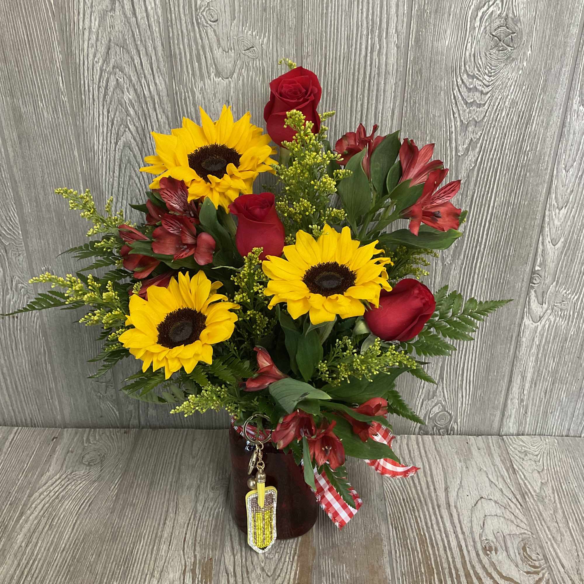 Bouquet of sunflowers, red roses, and red alstroemeria in a vase