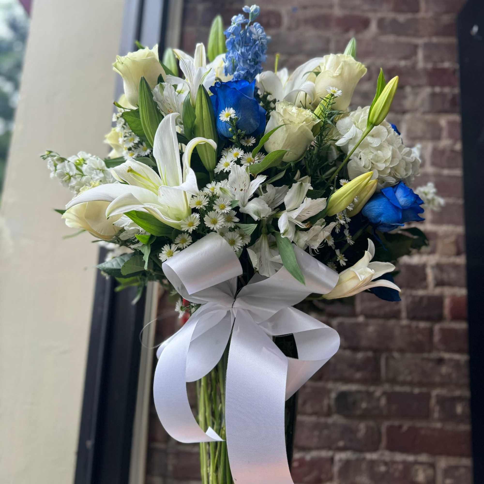An all white and blue bouquet is designed by experienced designers including