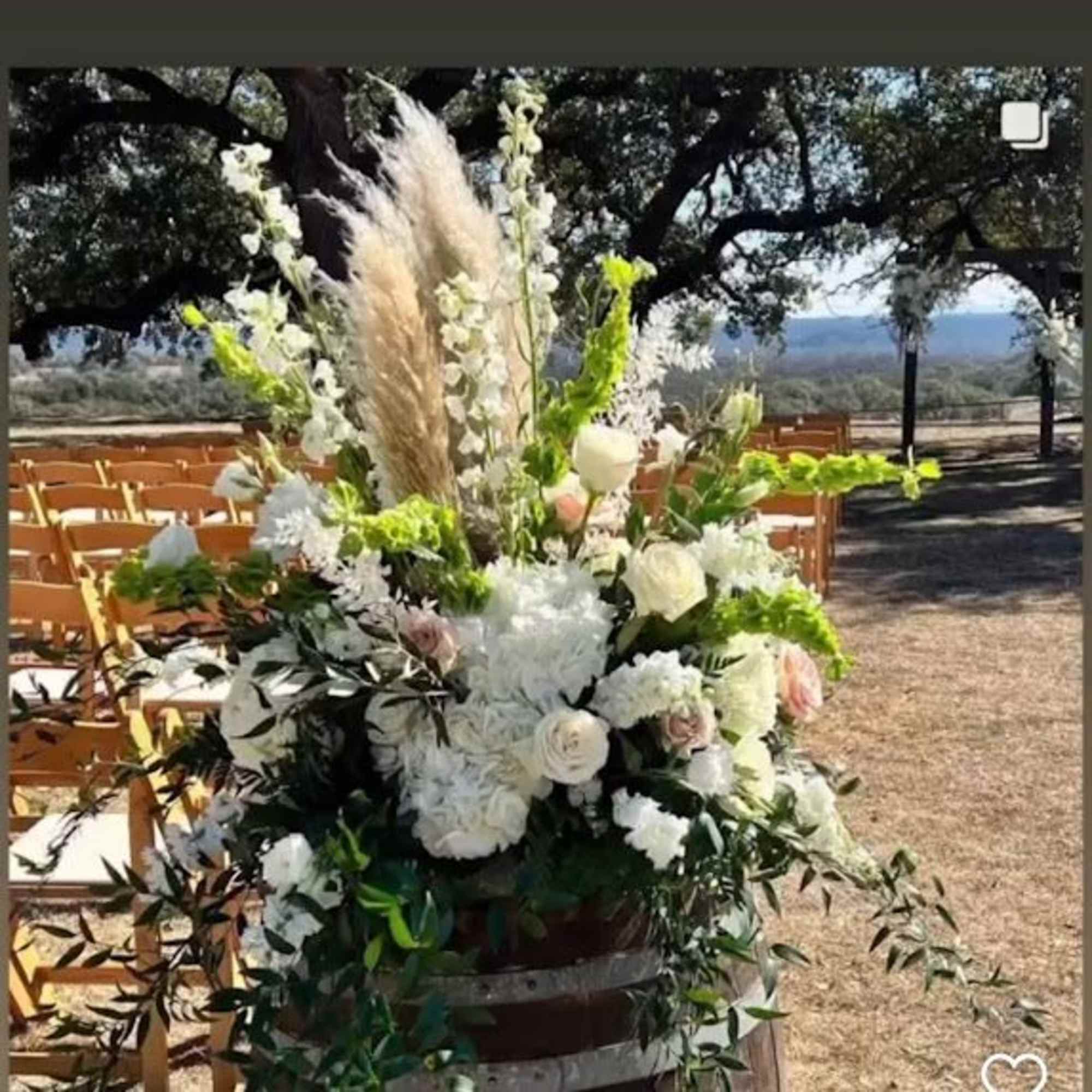 Tall white floral arrangement with pampas grass at an outdoor ceremony