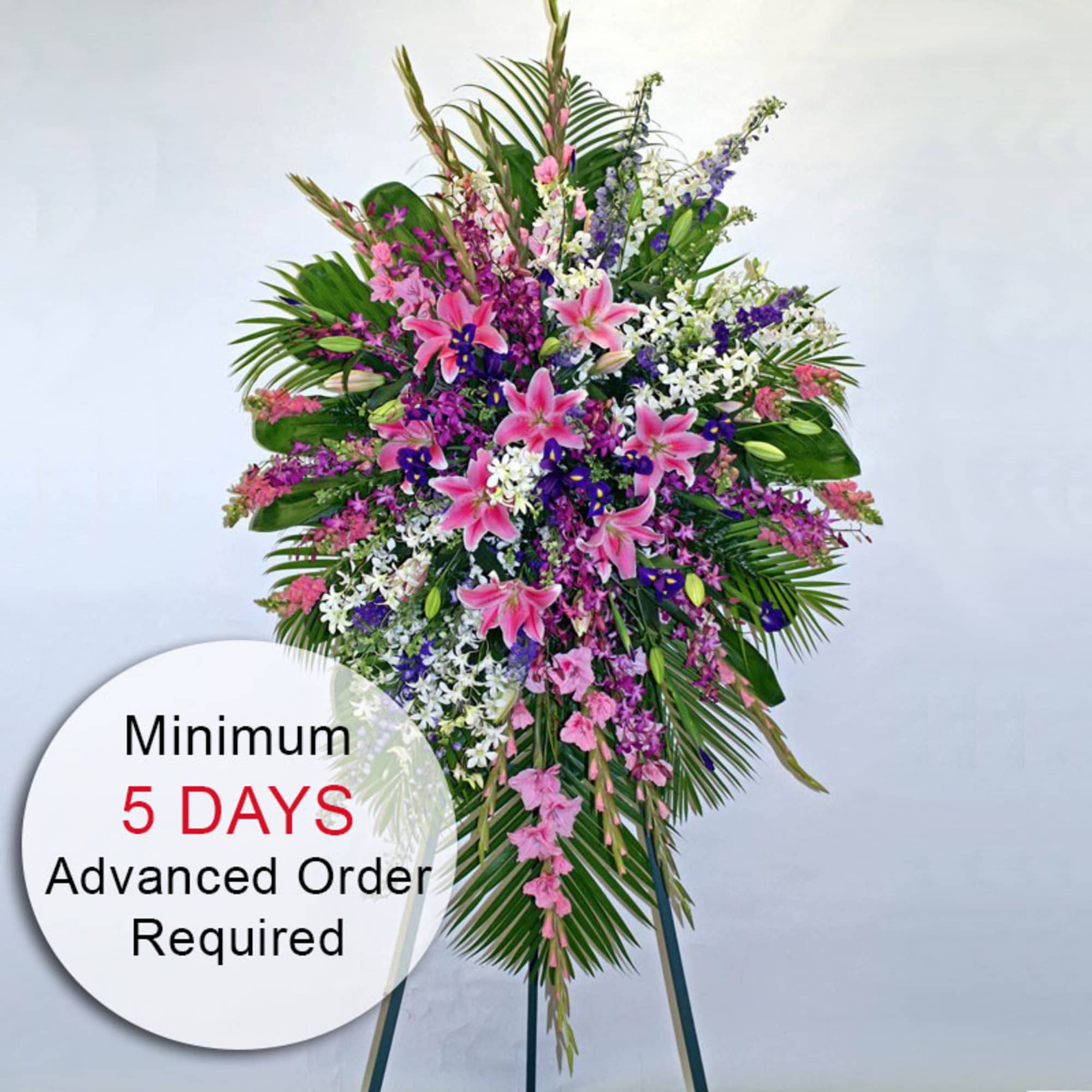 Tall standing spray of pink lilies and mixed purple and white flowers on an easel
