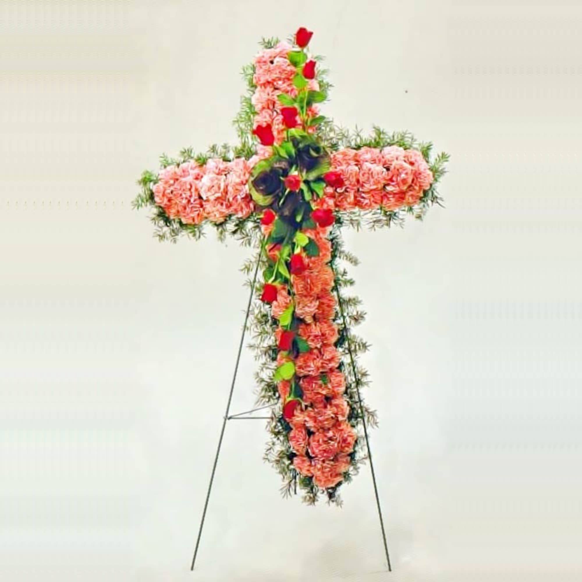 Standing cross of peach flowers with red roses on a metal easel