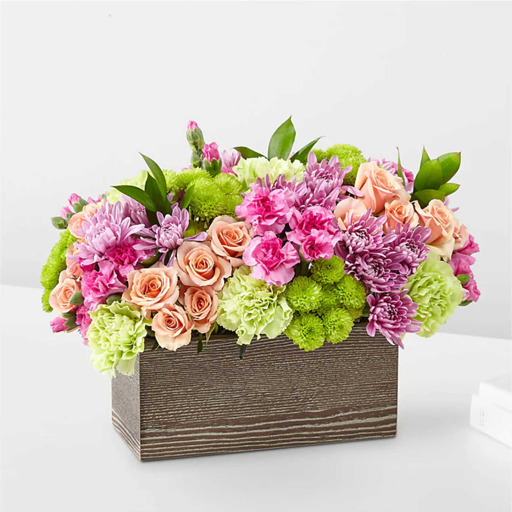 Mixed pink and peach flowers arranged in a rectangular wooden box