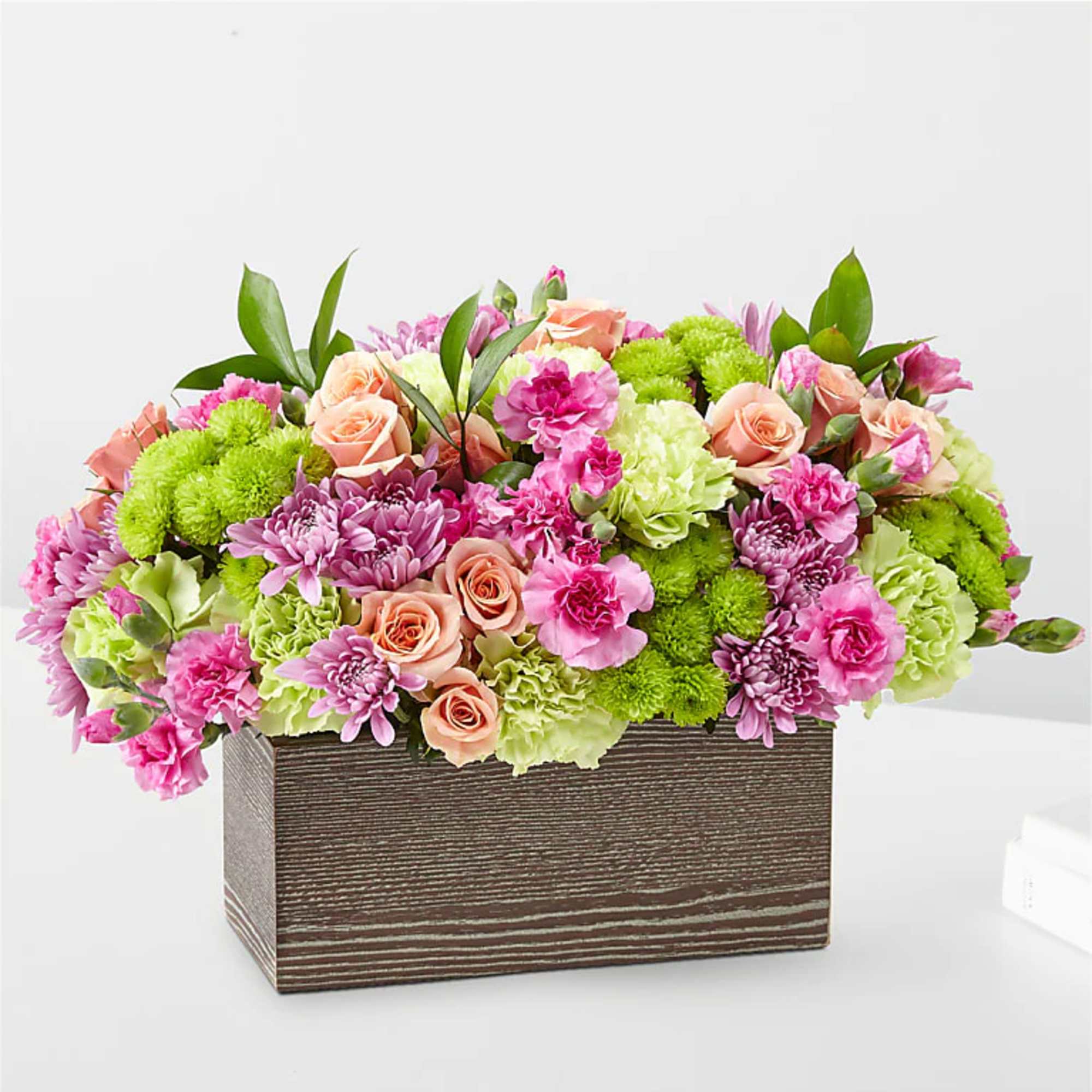 Pink and peach flowers arranged in a rectangular wooden box
