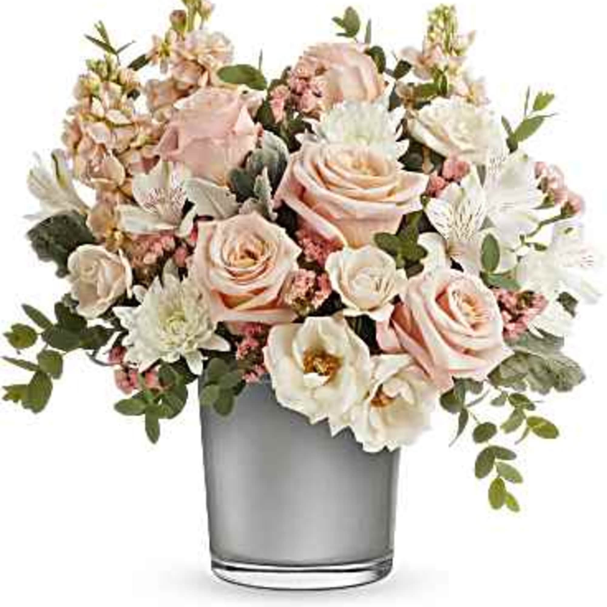 Blush roses and white flowers arranged in a clear glass vase