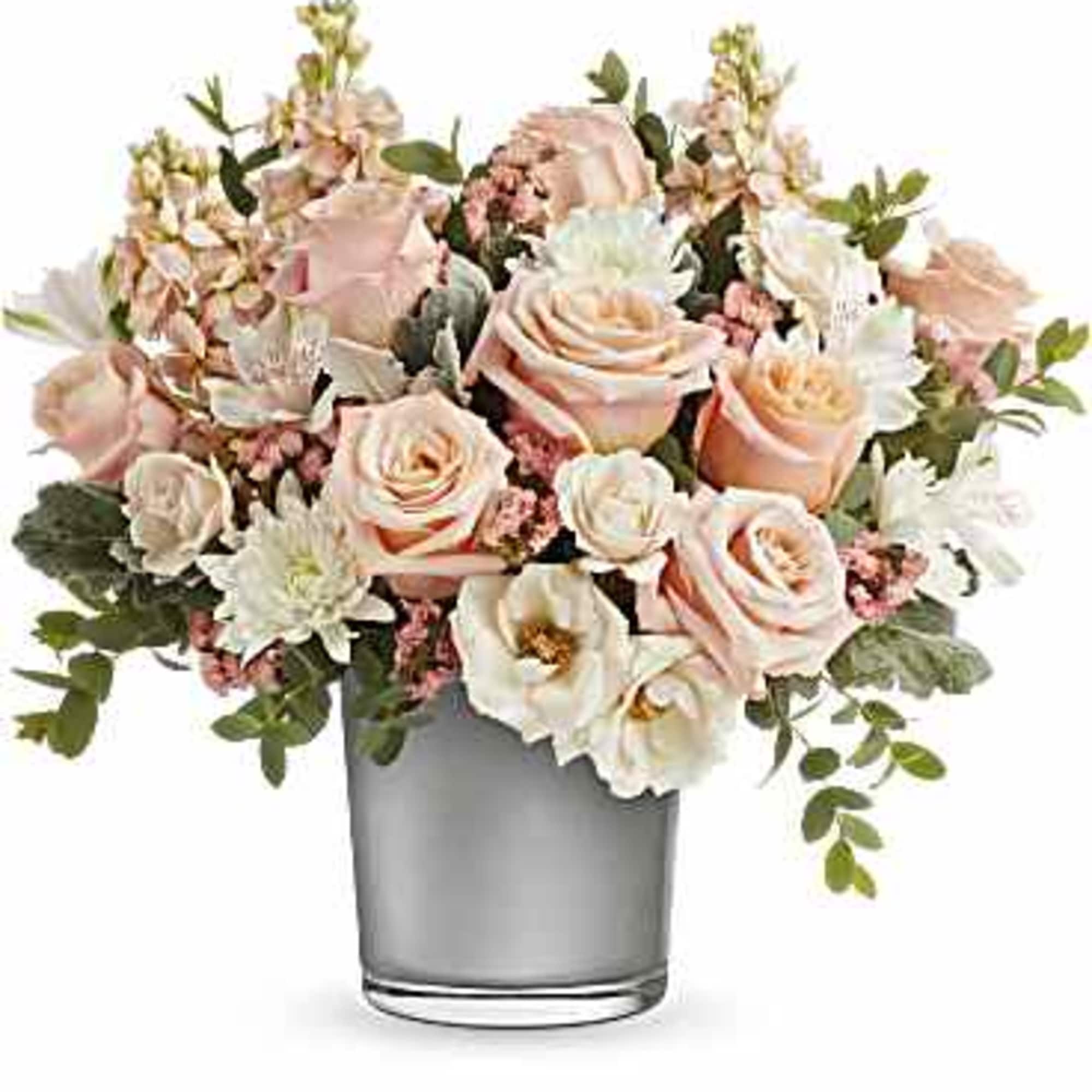Blush roses and white flowers in a clear glass vase