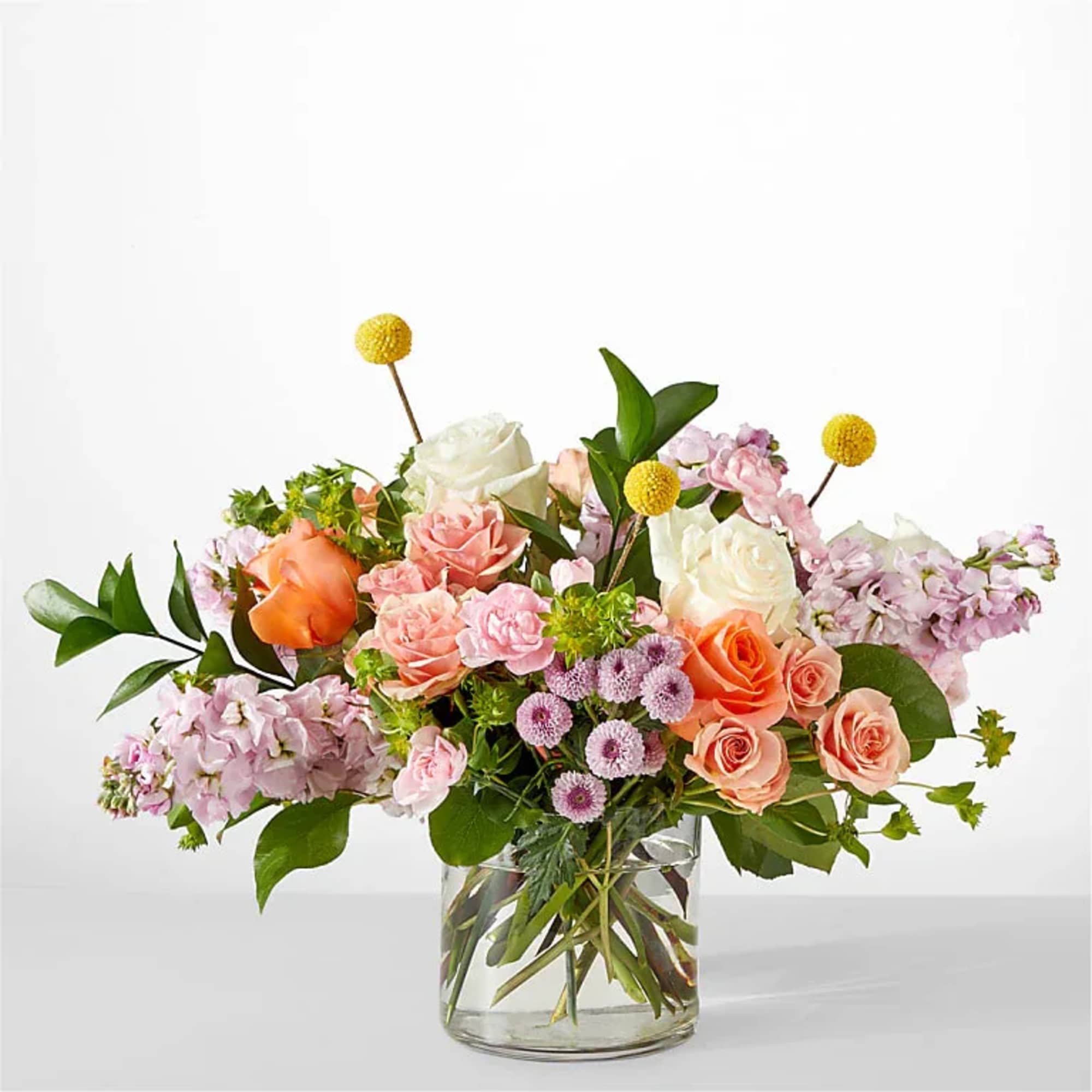 Mixed bouquet of roses and pink blooms in a clear glass vase
