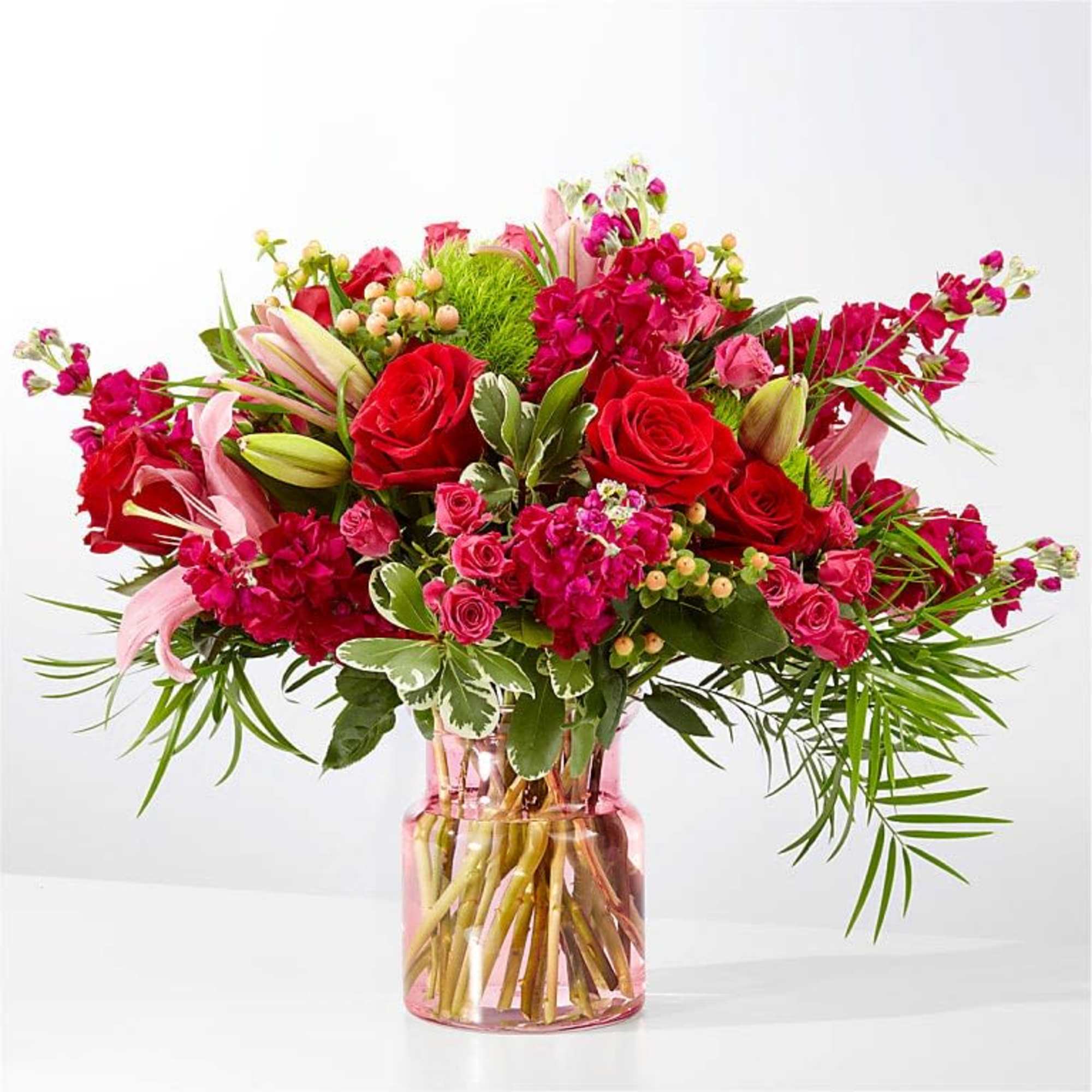 A lush bouquet of red and pink roses paired with pale pink