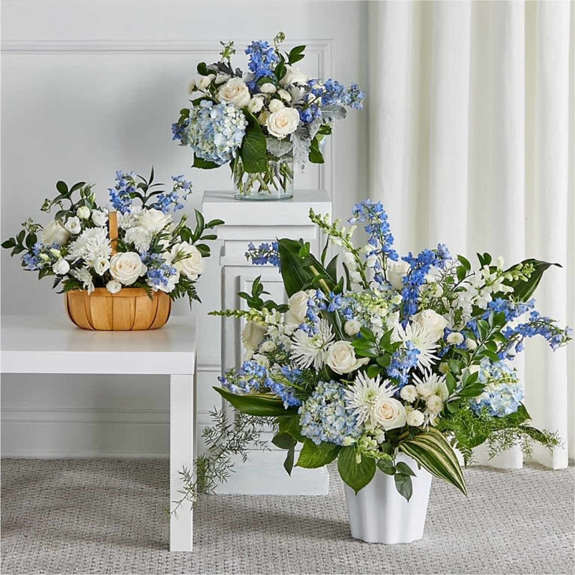 Soft blue delphinium spikes and pale hydrangea clusters meet classic white roses