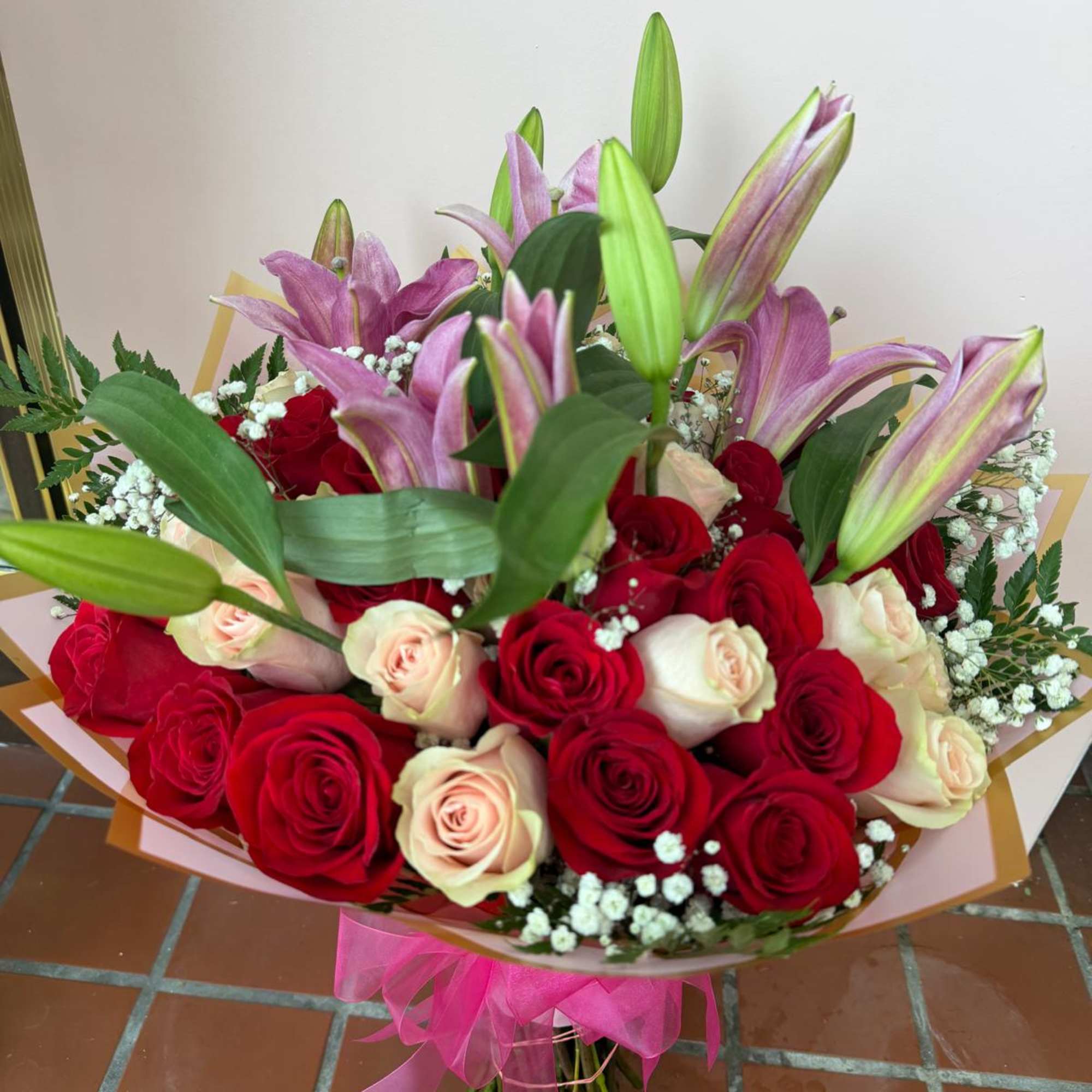 Bouquet of red and blush roses with pink lilies and baby's breath