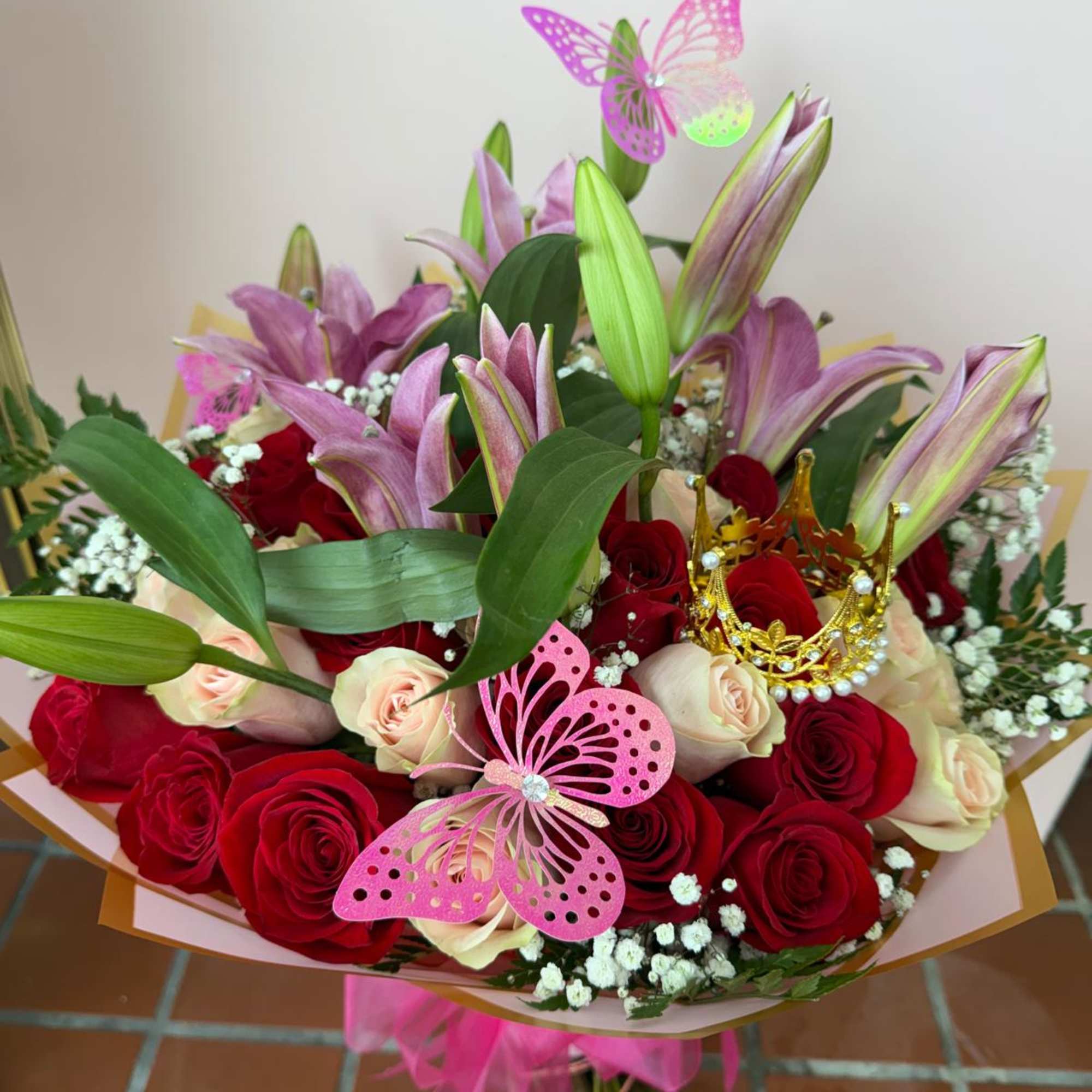 Bouquet of red and cream roses with pink lilies and butterfly decorations