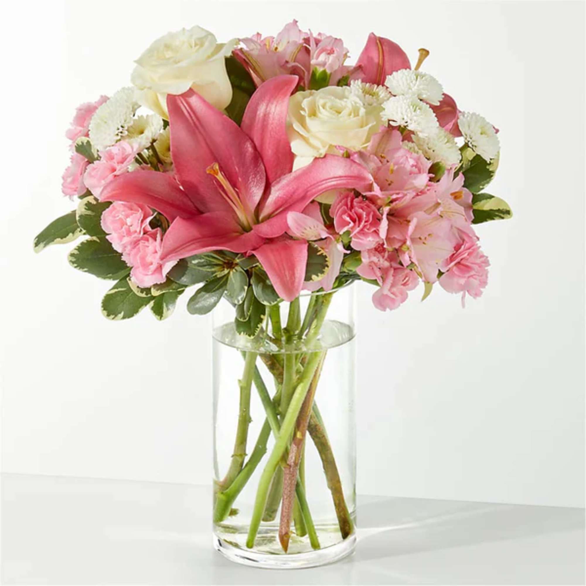 Pink lilies, roses, and carnations in a clear glass vase