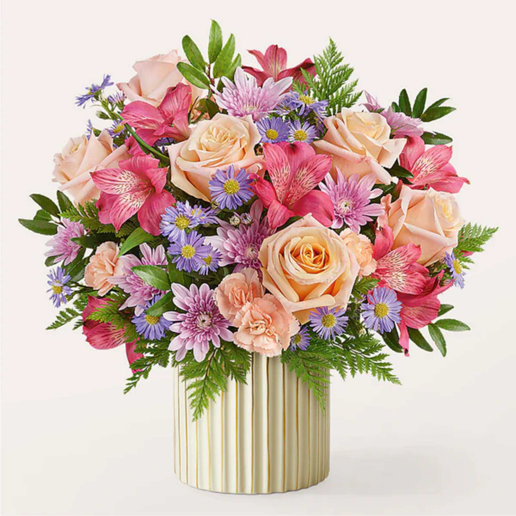 Mixed bouquet of peach roses, pink flowers, and purple daisies in a gold vase