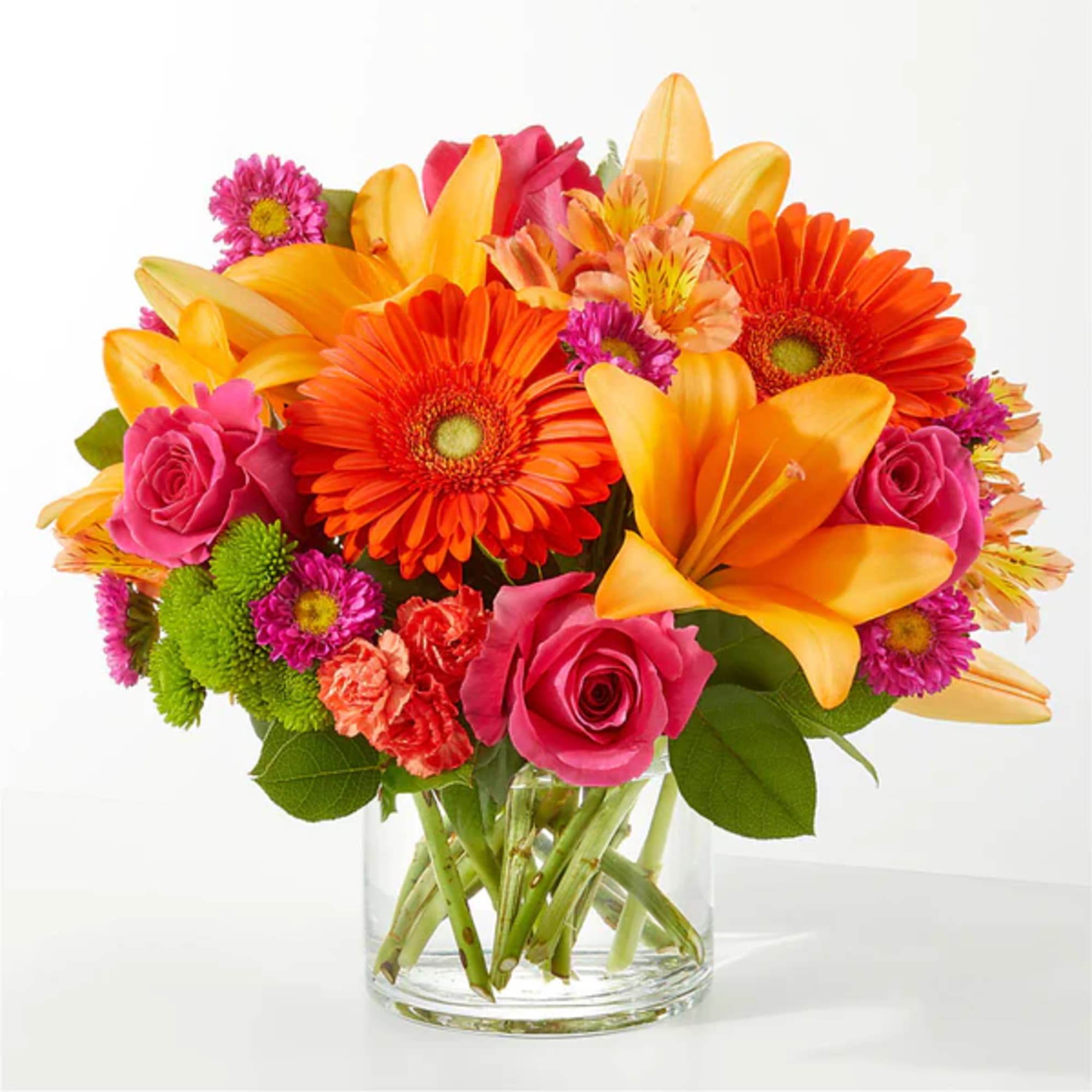 Bright mixed bouquet of lilies, gerbera daisies, roses, and carnations in a glass vase