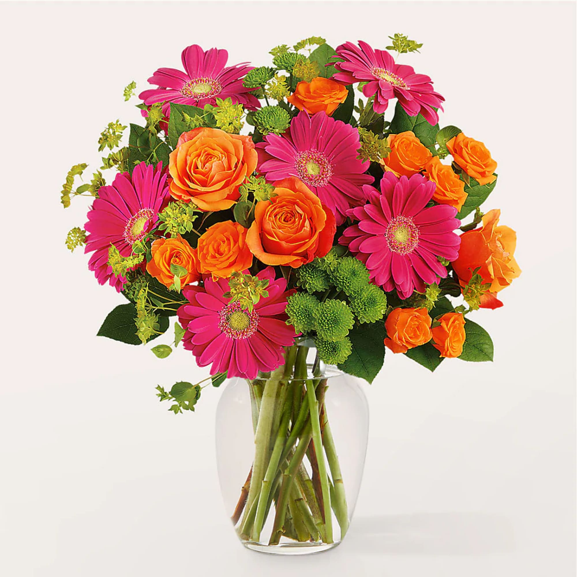 Bouquet of pink gerbera daisies and orange roses in a clear glass vase