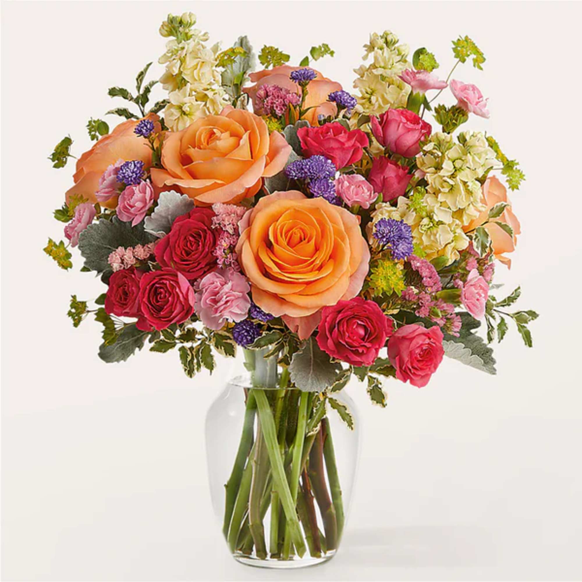 Mixed bouquet of orange and pink roses in a clear glass vase