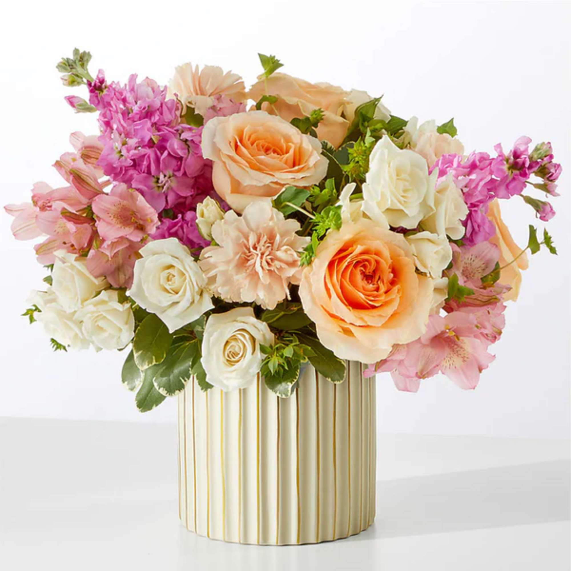 Pink and peach roses with pink alstroemeria in a striped vase
