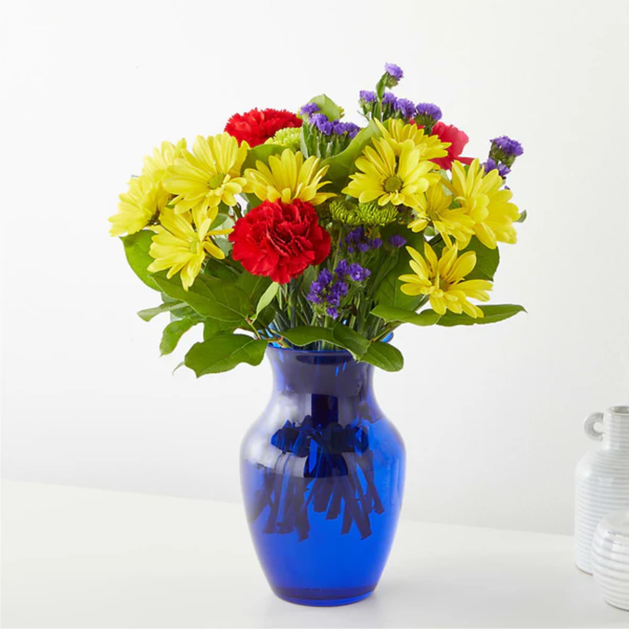 Yellow daisies and red carnations in a blue glass vase