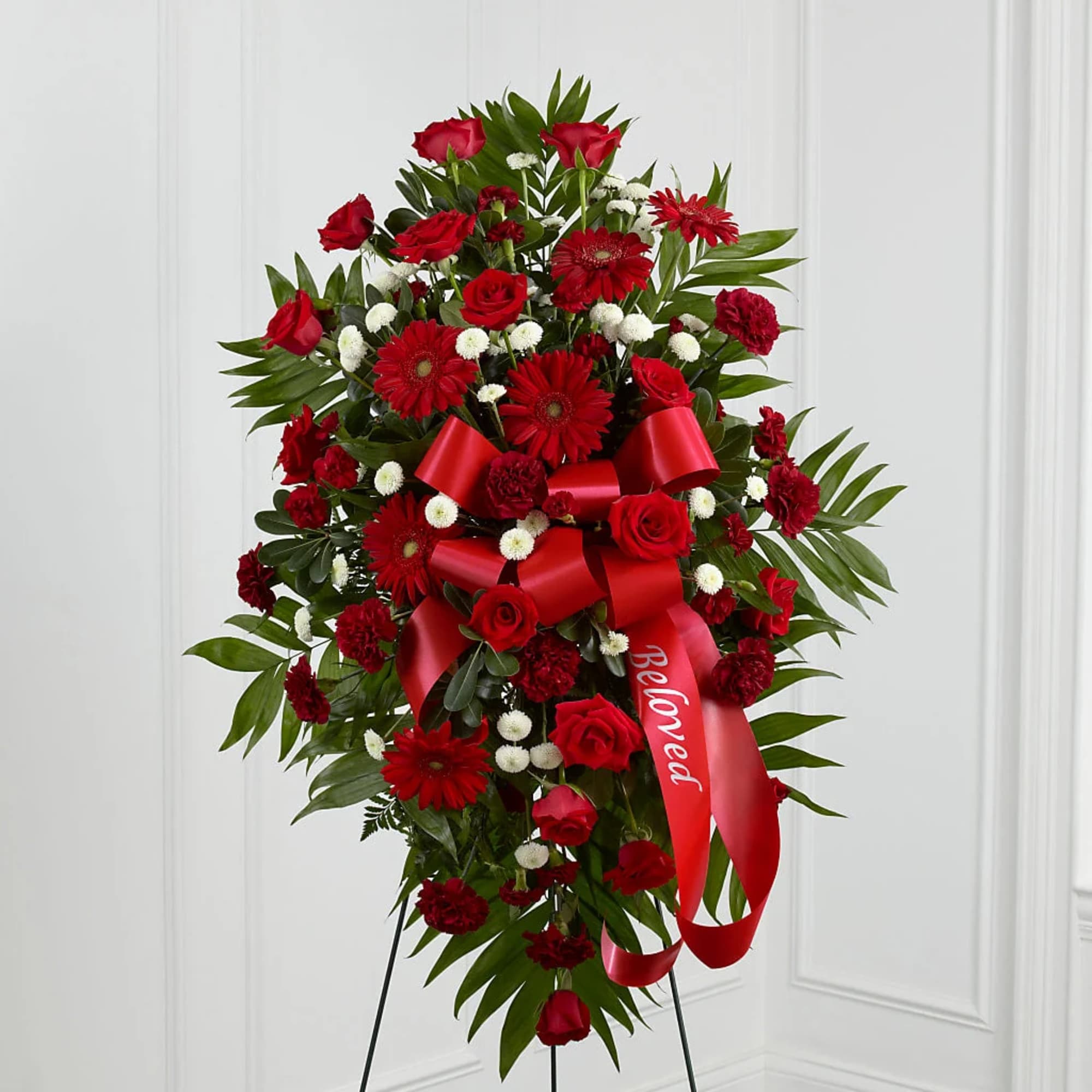 Red floral standing spray with roses, gerbera daisies, and a red ribbon