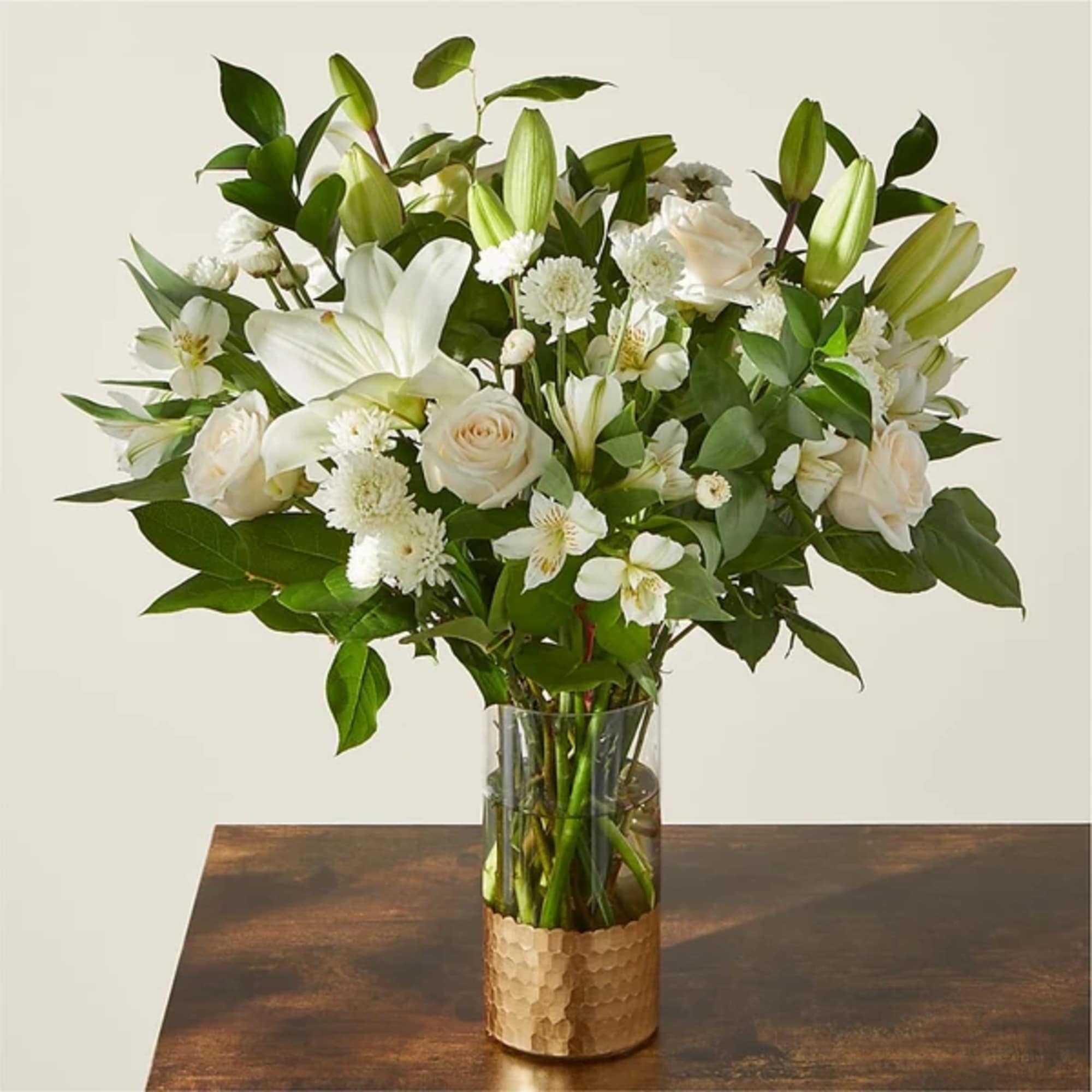 White lilies and roses arranged in a clear glass vase