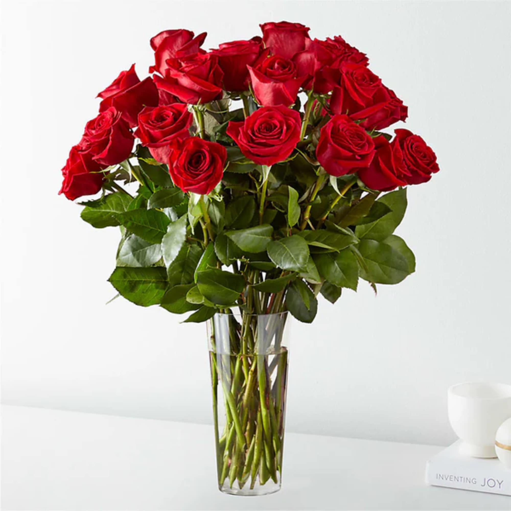 Tall bouquet of red roses in a clear glass vase