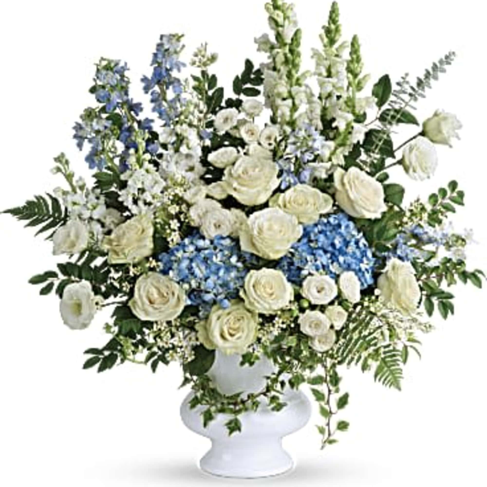 White and blue floral arrangement in a white pedestal vase