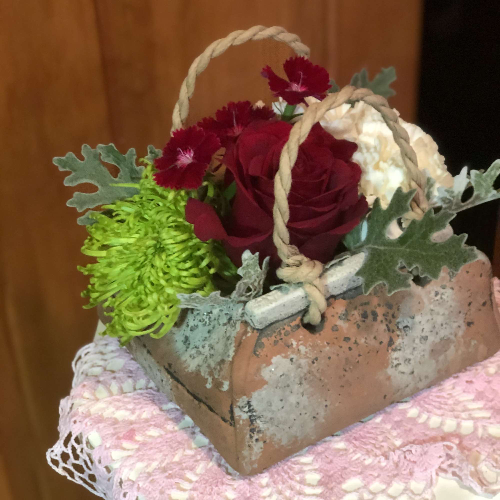 Small basket arrangement with red roses, green chrysanthemum, and cream blooms